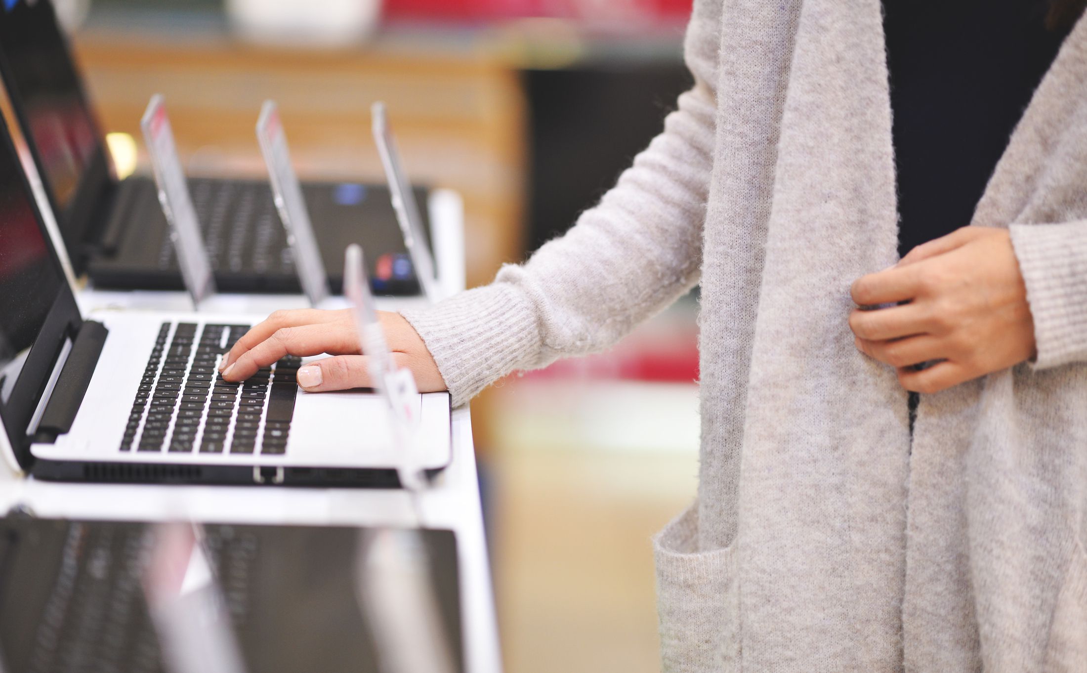 Woman chooses the laptop in electronics store, shoot with Nikon lens105 mm f/1.4