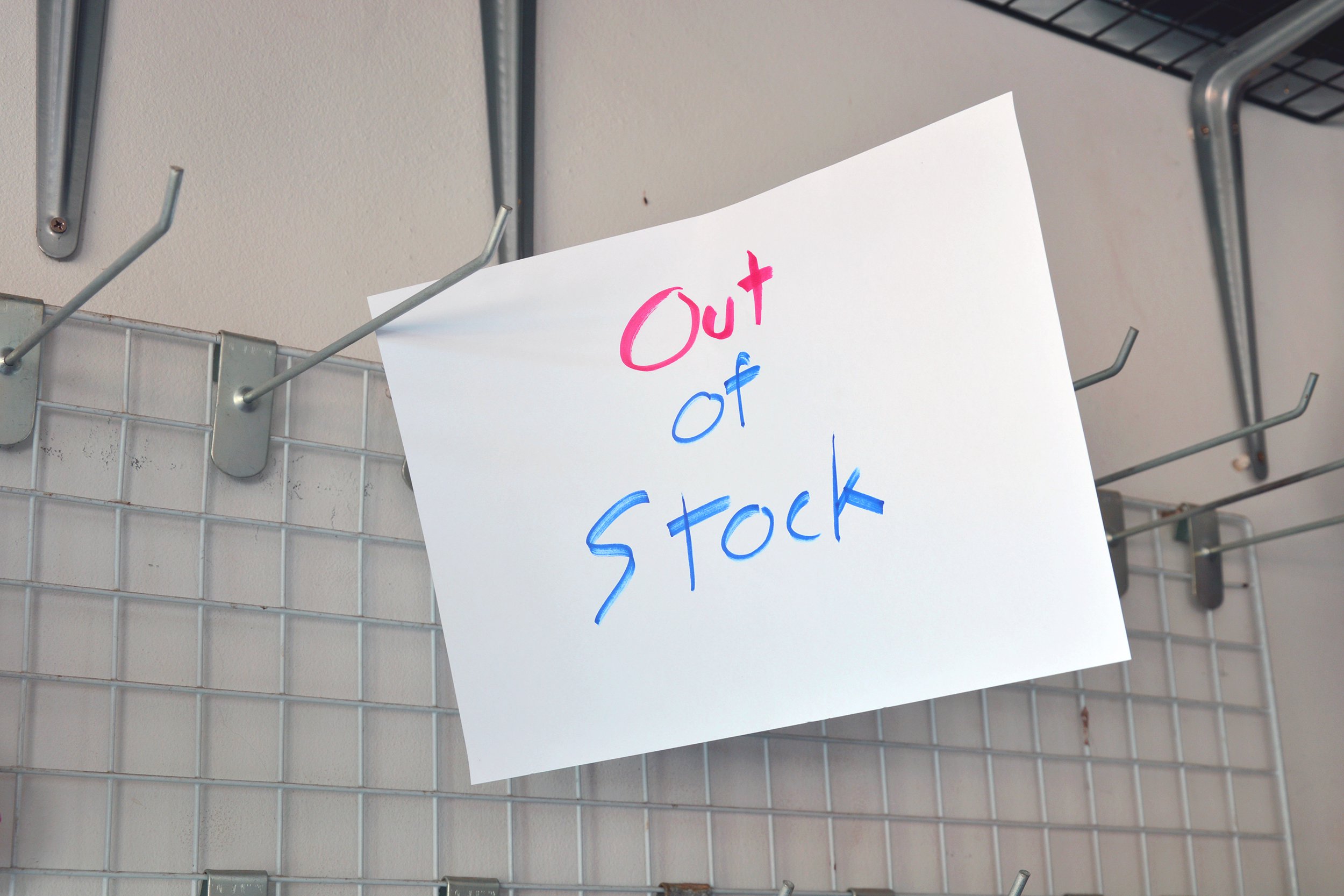 Out of Stock sign on an empty store shelf