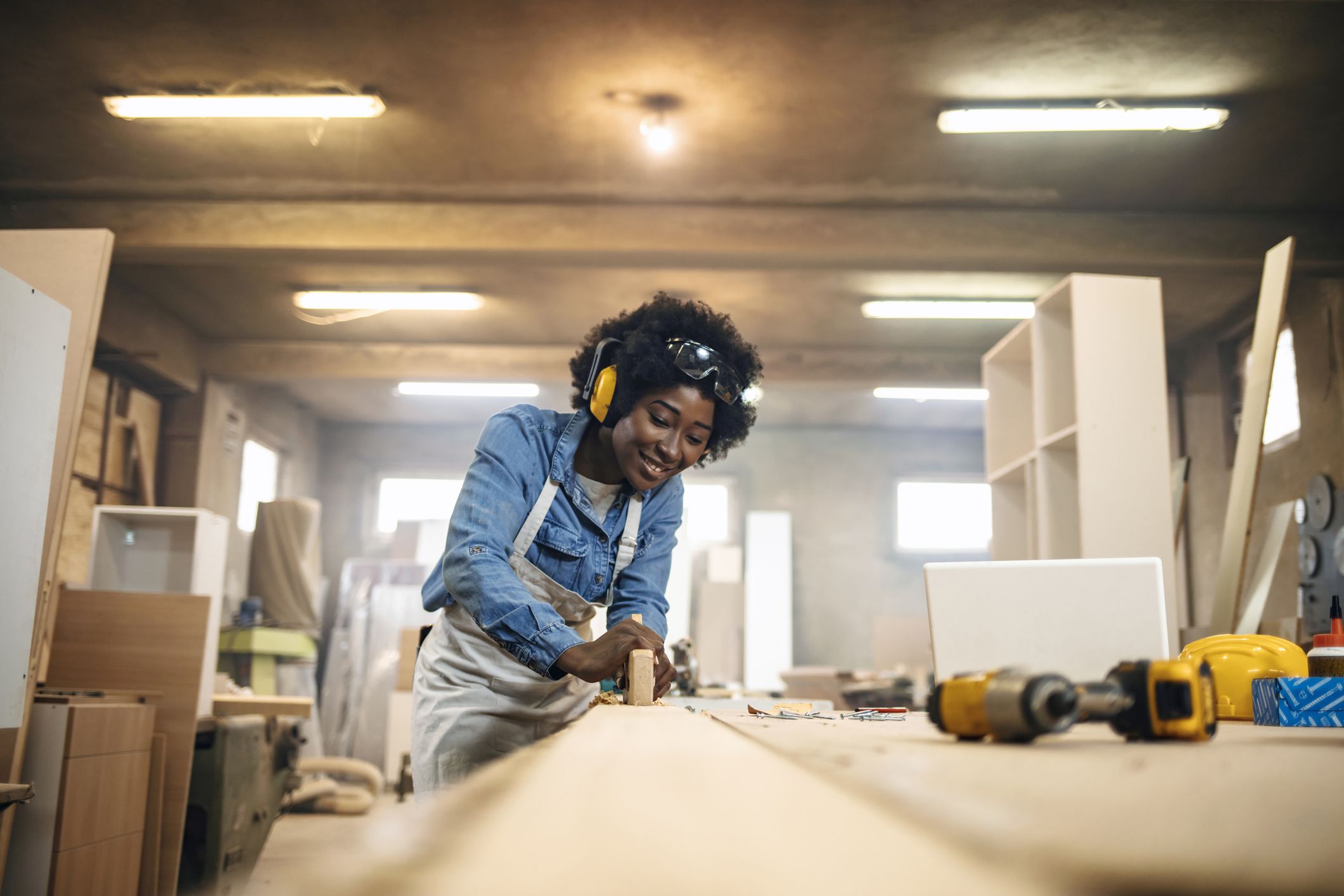 One African-American female carpenter working with wood in her workshop.