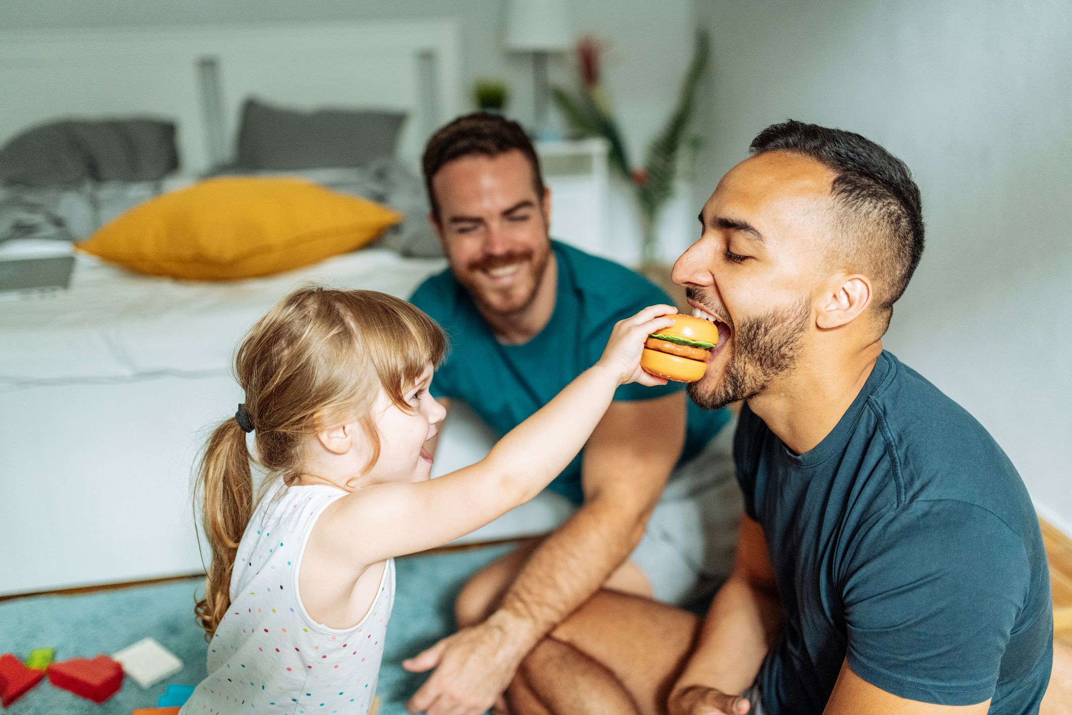 Gay couple playing with their adopted daughter girl and enjoying the parenthood
