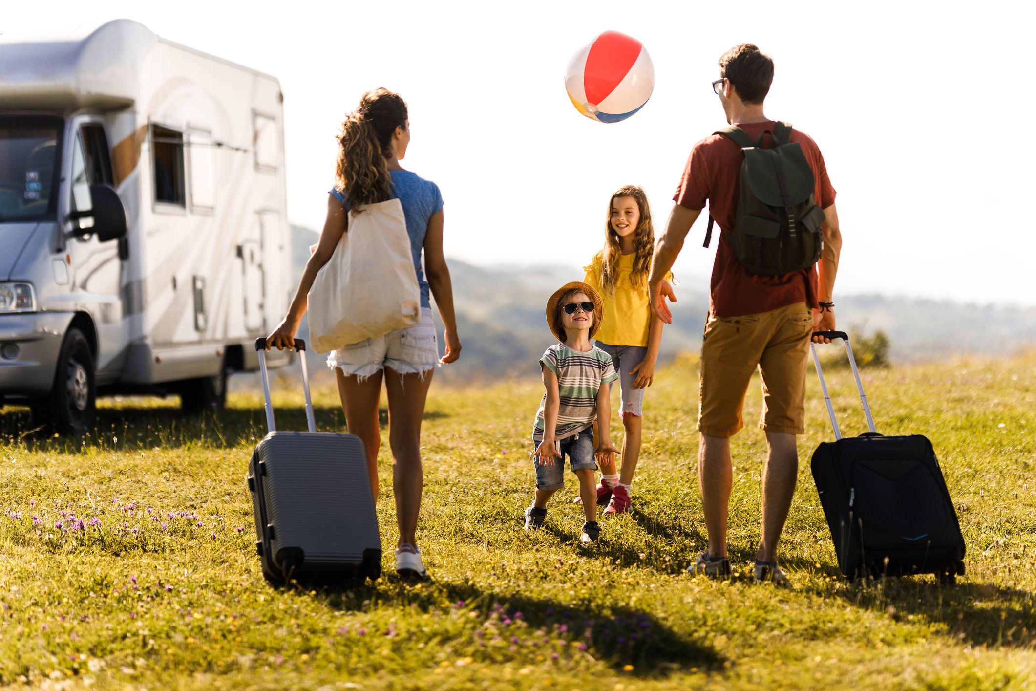 Happy kids enjoying with their parents while arriving on their summer vacation at trailer park.