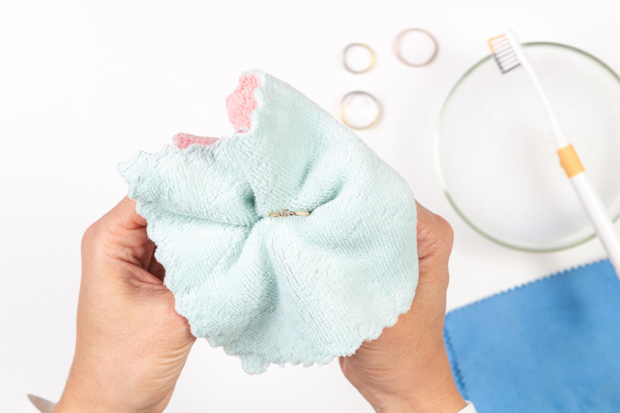 Woman hands cleaning and polishing golden jewelry at home. Top view.