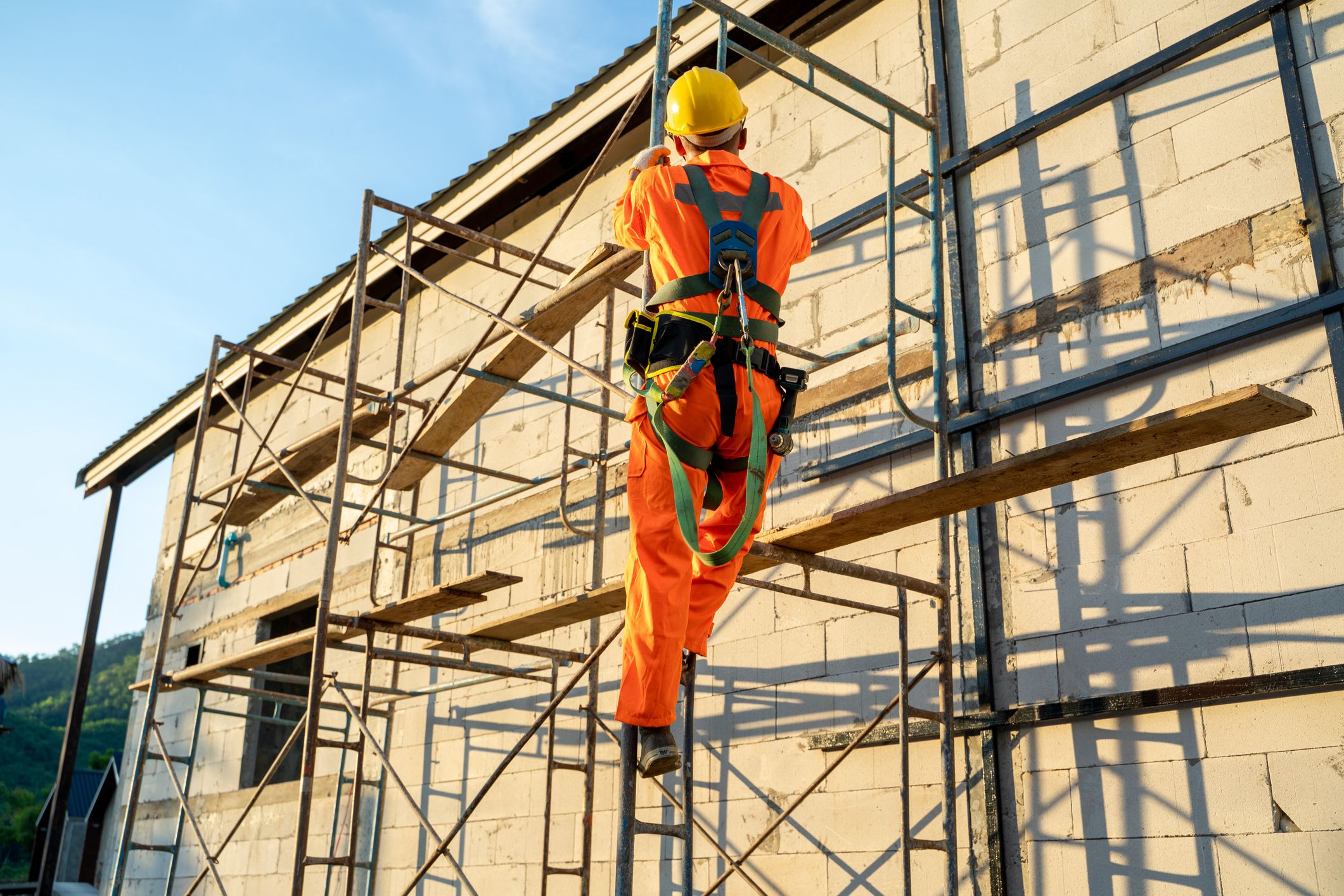 Construction worker wearing safety harness belt during working at high place at construction site.