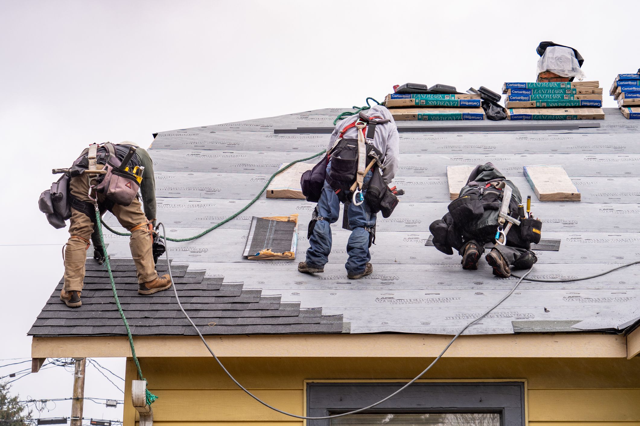 Everett WA. USA - 03-23-2021: Crew Installing New Shingles on Roof on a Rainy Day