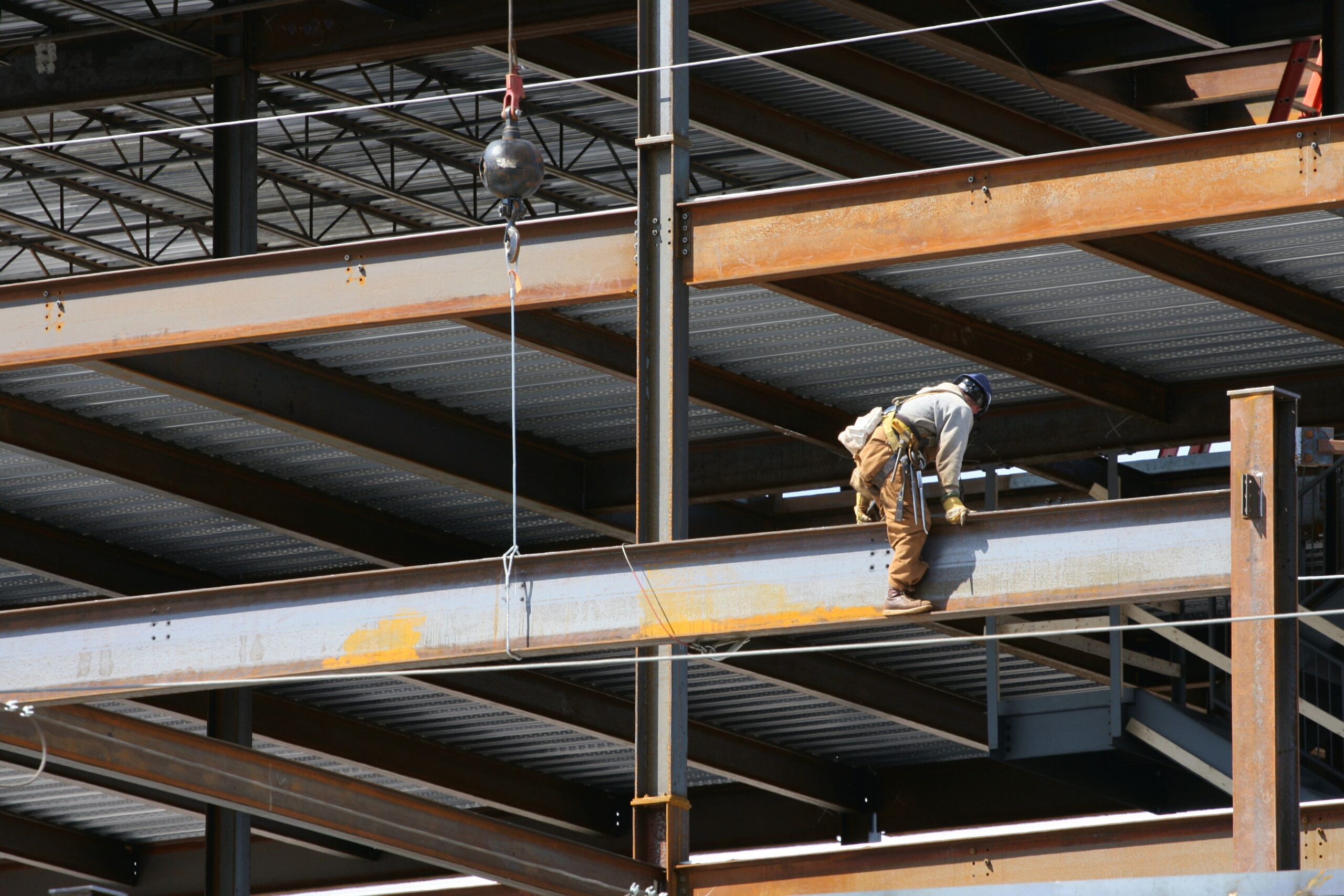 Steel frame construction on an office building with an ironworker maneuvering a steel beam into place.