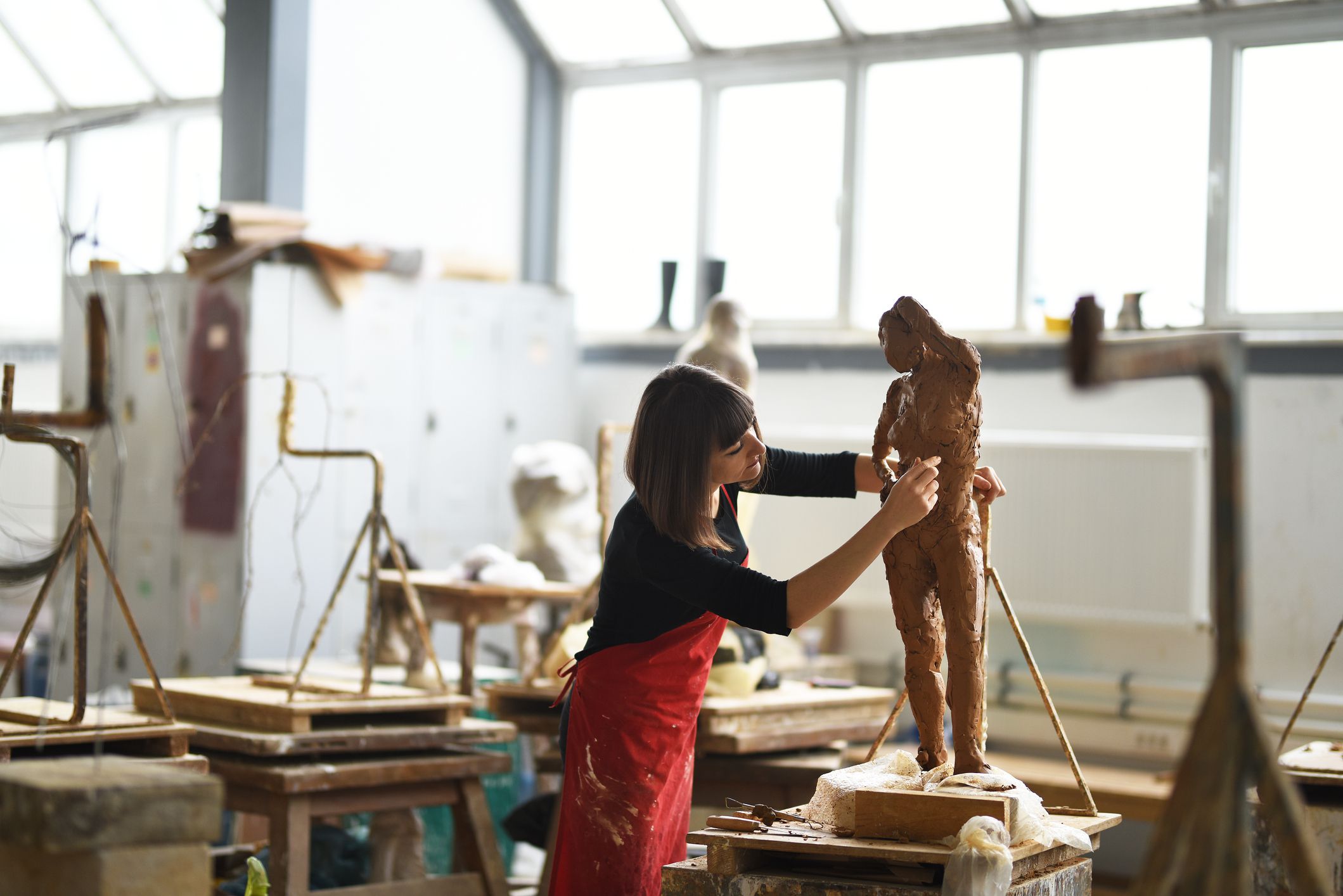 Young Female Sculptor is working in her studio