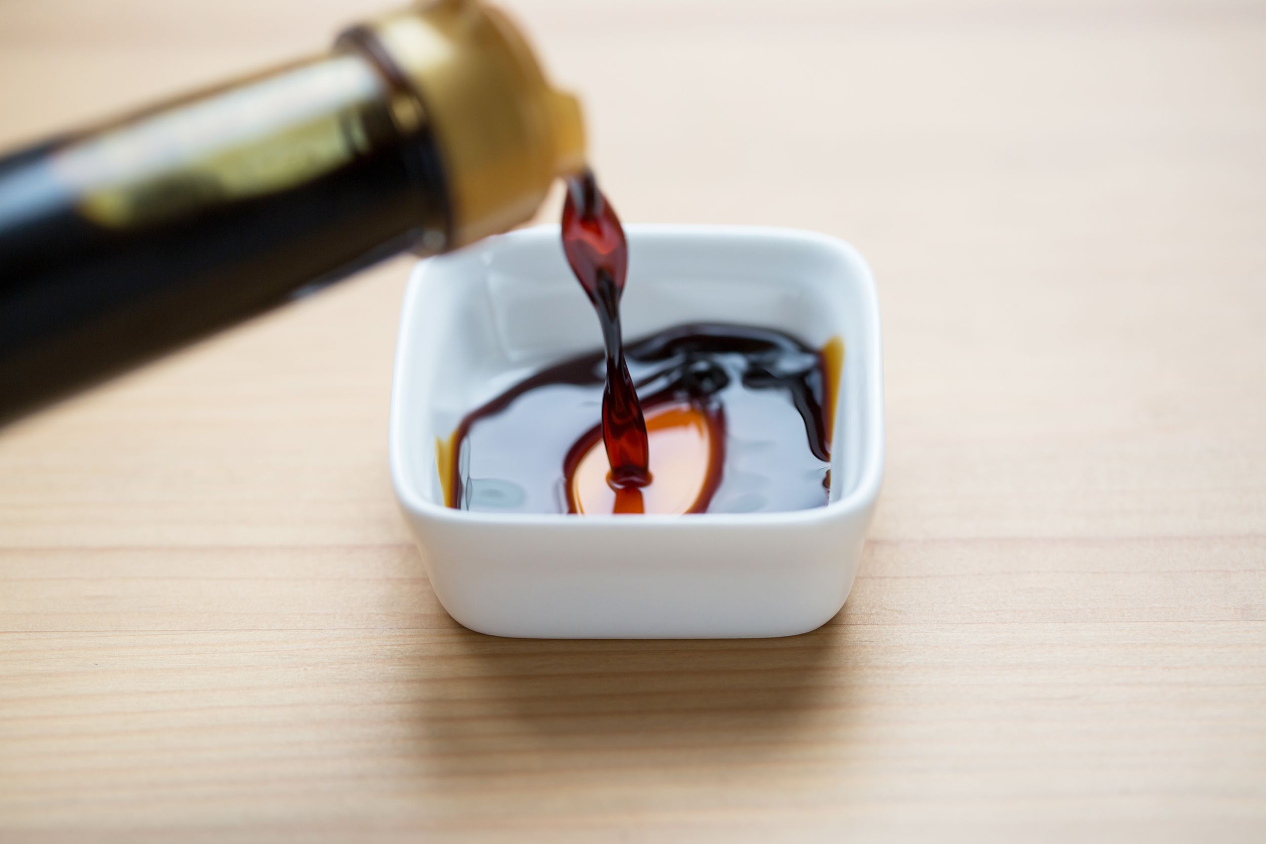 soy sauce being poured into white bowl