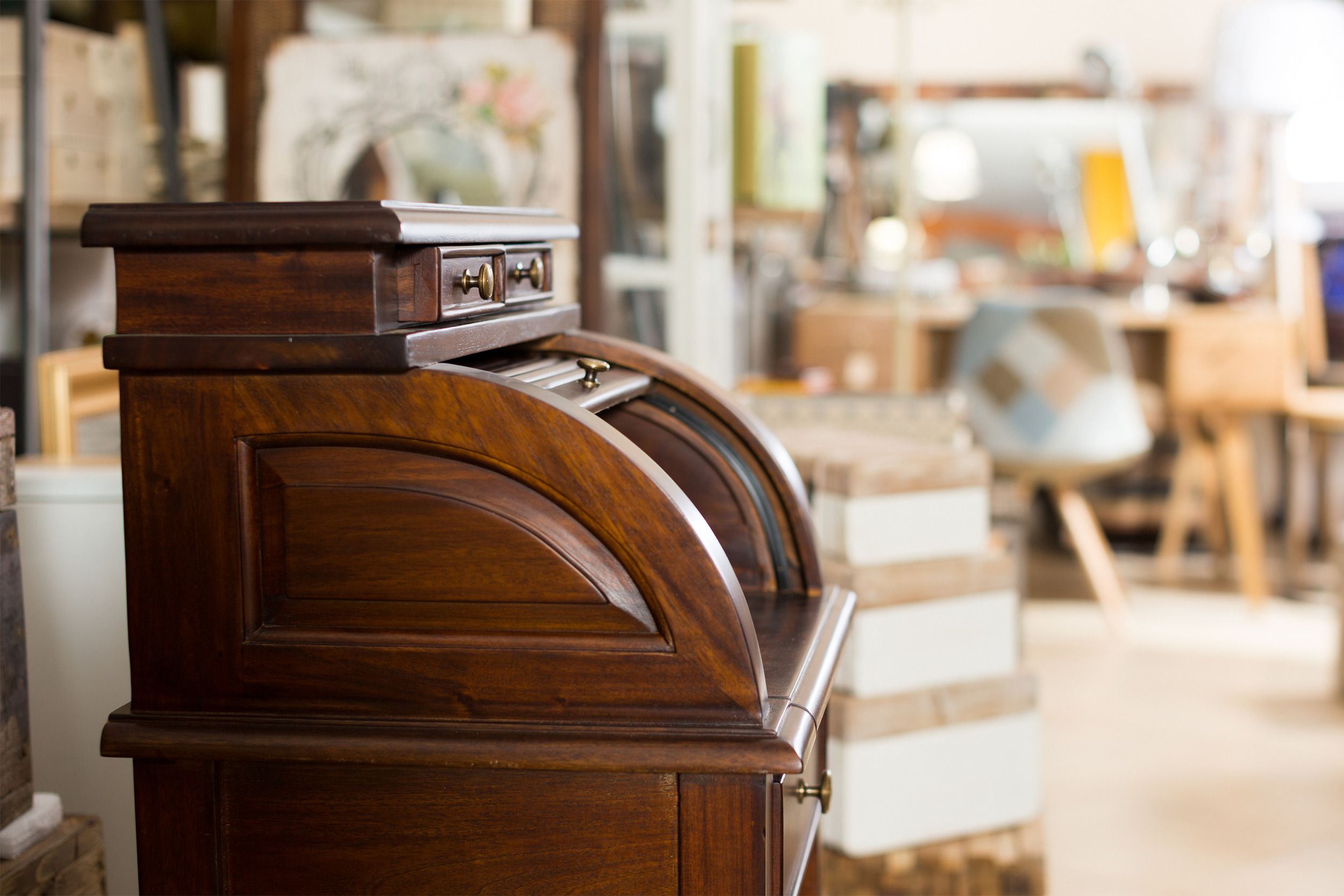 Closeup of a wooden antique desk in an antique shop with a blurred background of numerous antiques