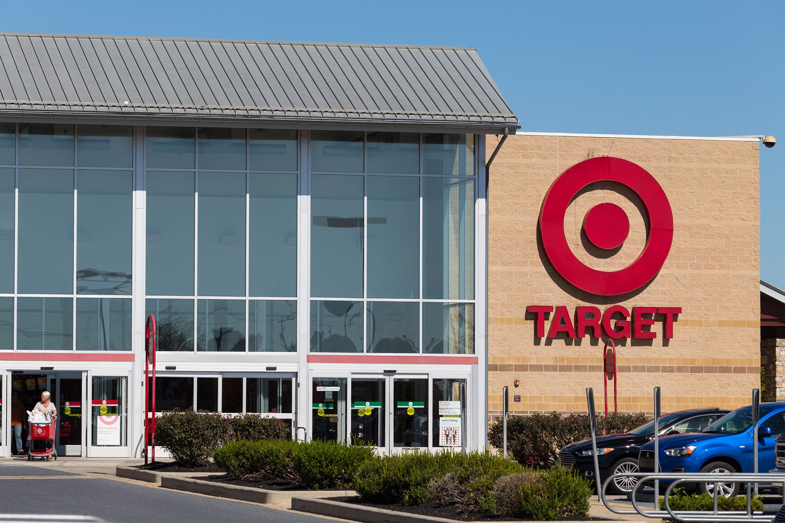 Front exterior of a Target store in Lancaster, Pennsylvania, a person with a shopping cart exiting through the door, with shrubbery and cars parked in the parking lot