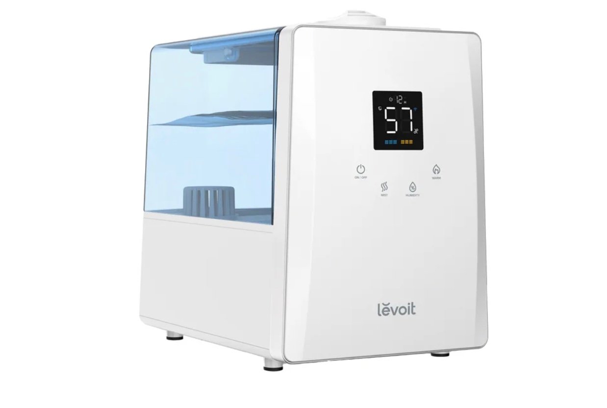 A white Levoit humidifier with a transparent blue water tank and a digital display showing 57%. The front panel includes touch buttons and the brand logo near the bottom—perfect for those seeking Costco deals for seniors.