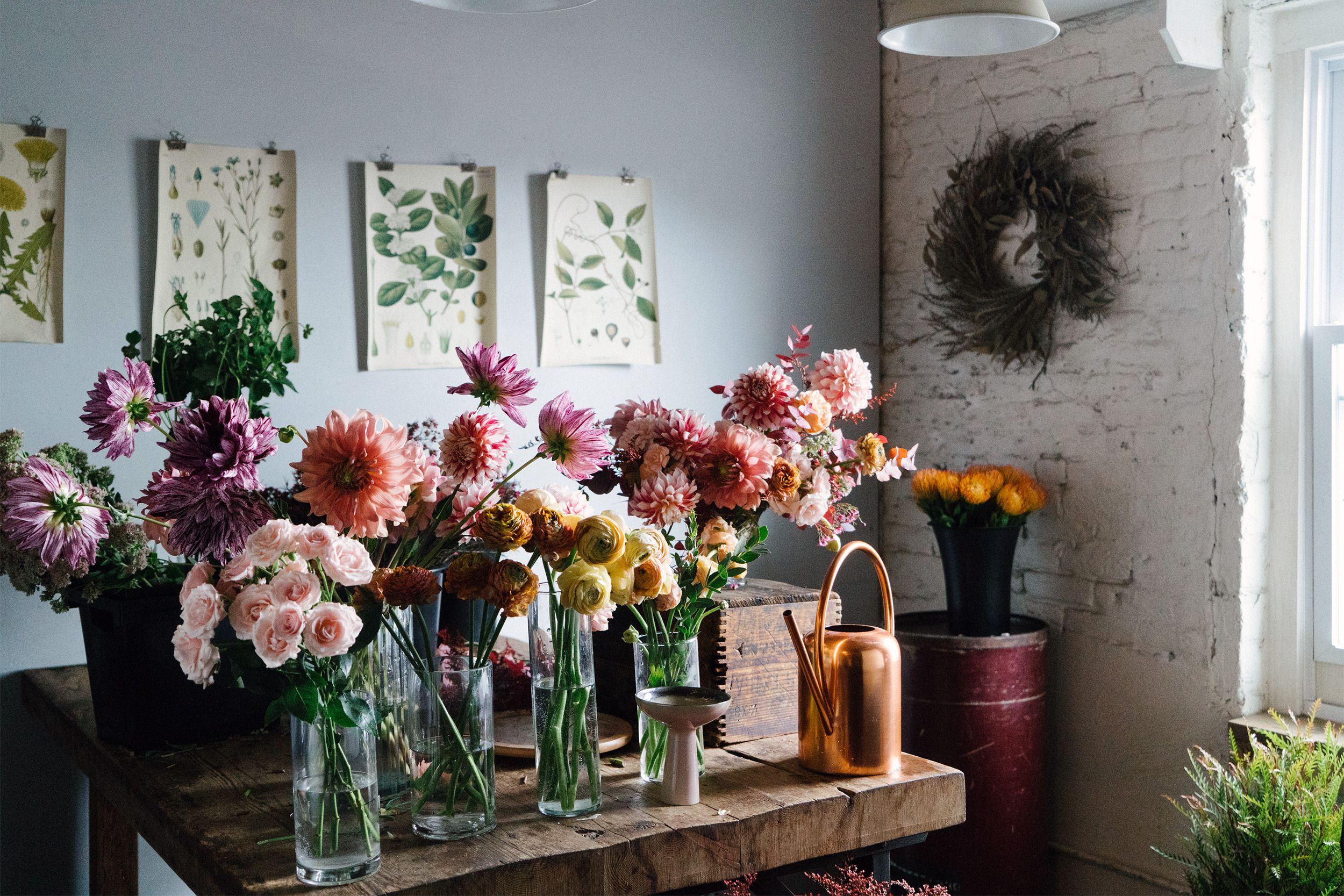 Many floral arrangements in glass vases on rustic wooden table in a floral shop