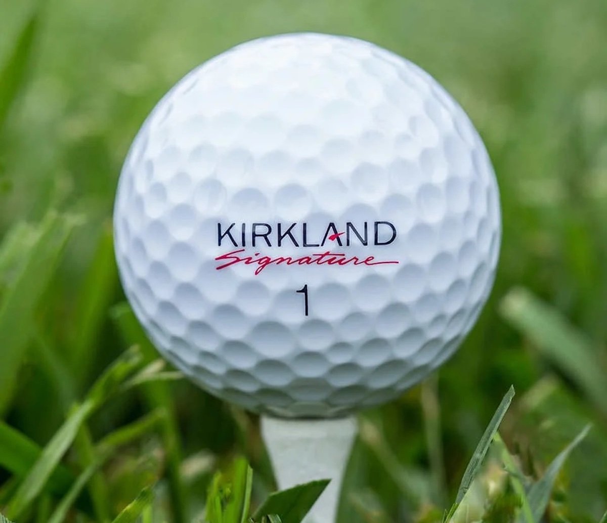 A white Kirkland Signature golf ball marked with the number 1 sits on a tee, surrounded by green grass—perfect for enjoying the game and taking advantage of Costco deals for seniors.