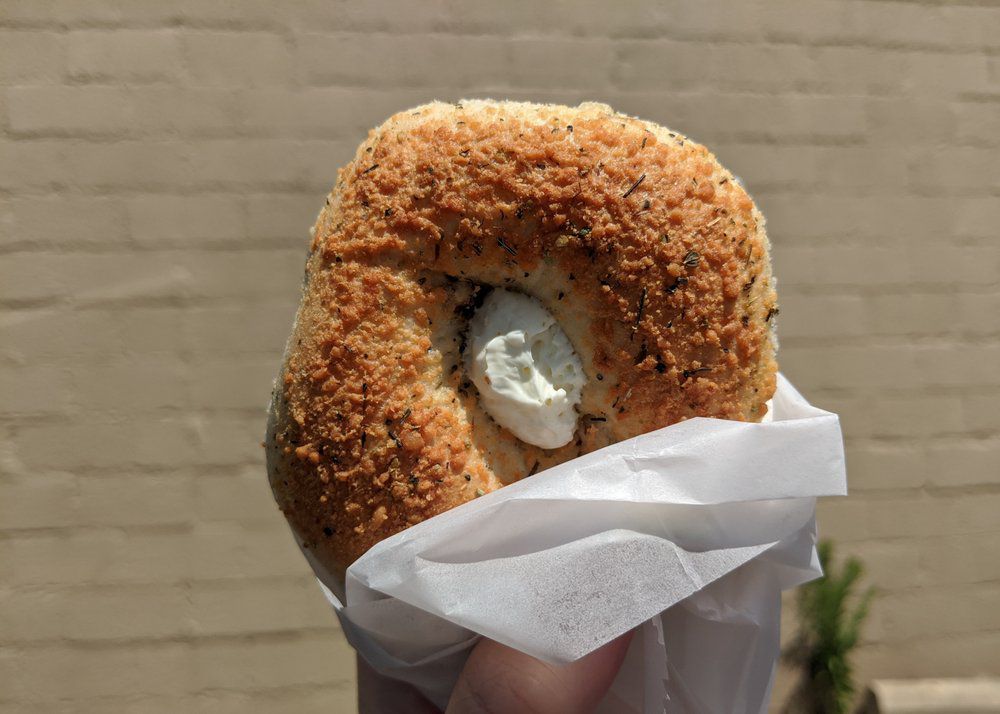 New York Bagel parmesan bagel held in the air