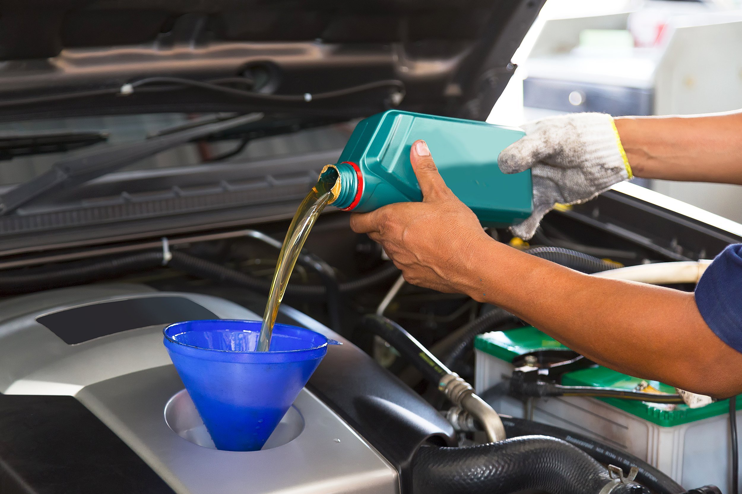 car mechanic replacing and pouring fresh oil into engine