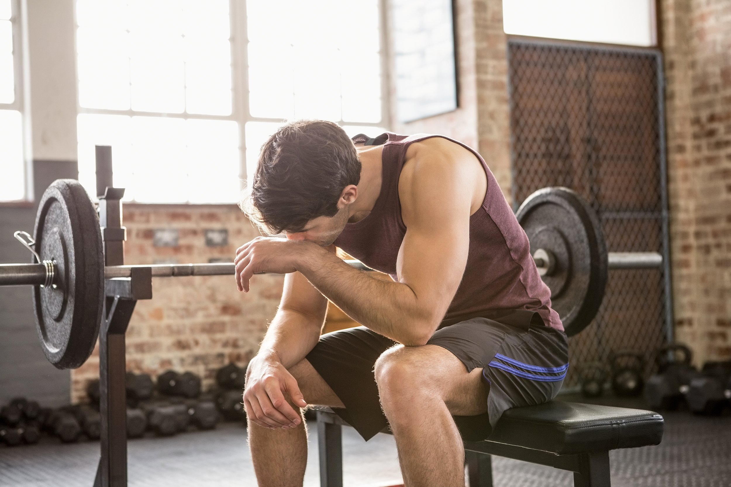 tired man sitting on the bench at the gym