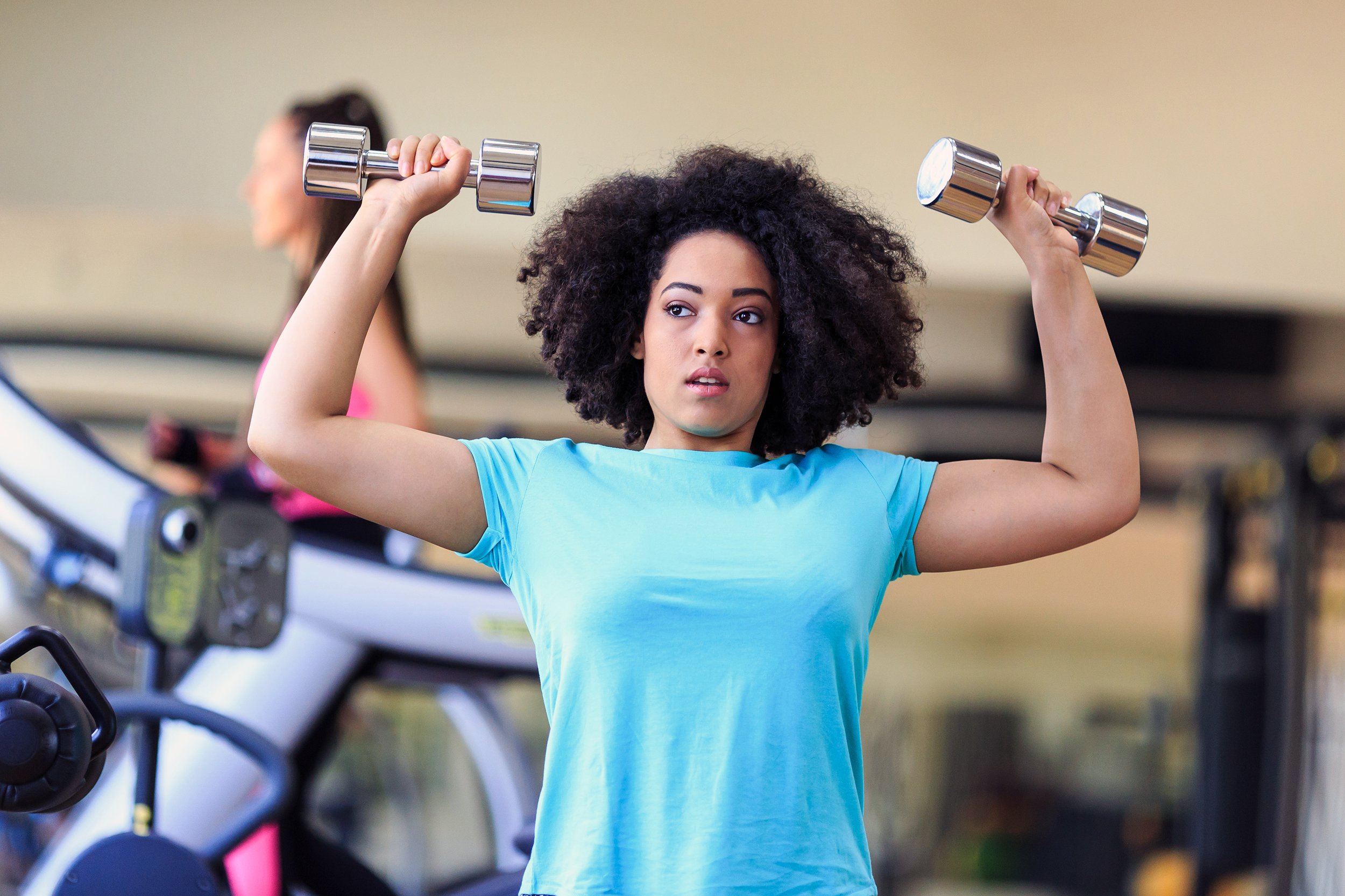 Nervous looking woman lifting dumbbells at the gym