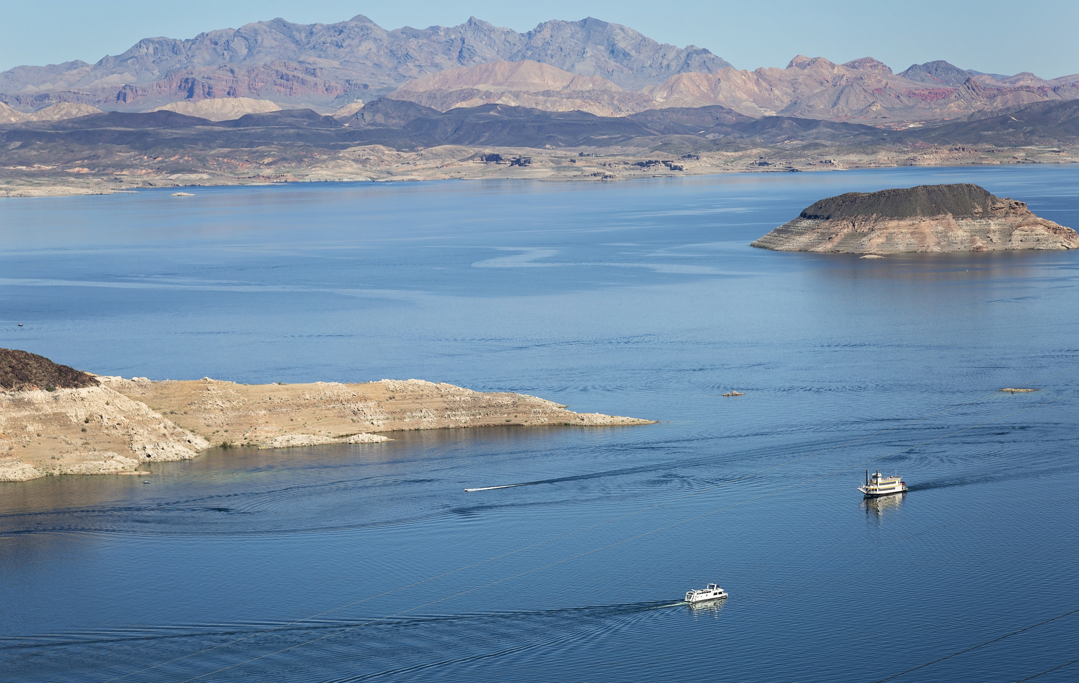 Aerial of Lake Mead, Nevada, two boats in the water, expansive view of mountains in the background, on a sunny day