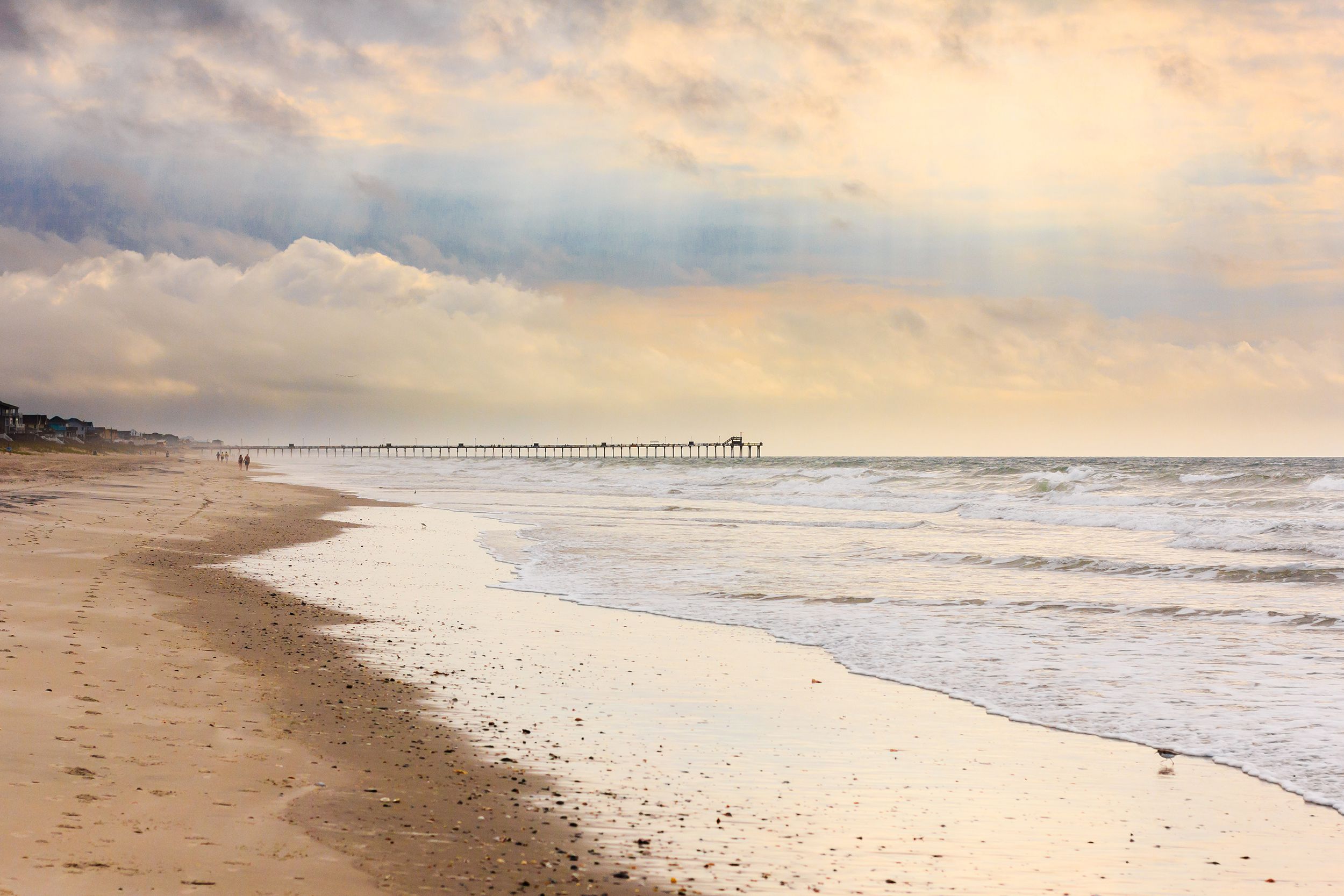 Beach and bogue inlet fishing pier at Emerald Isle, North Carolina during late sunrise, ethereal clouds with oranges, blues, and purples