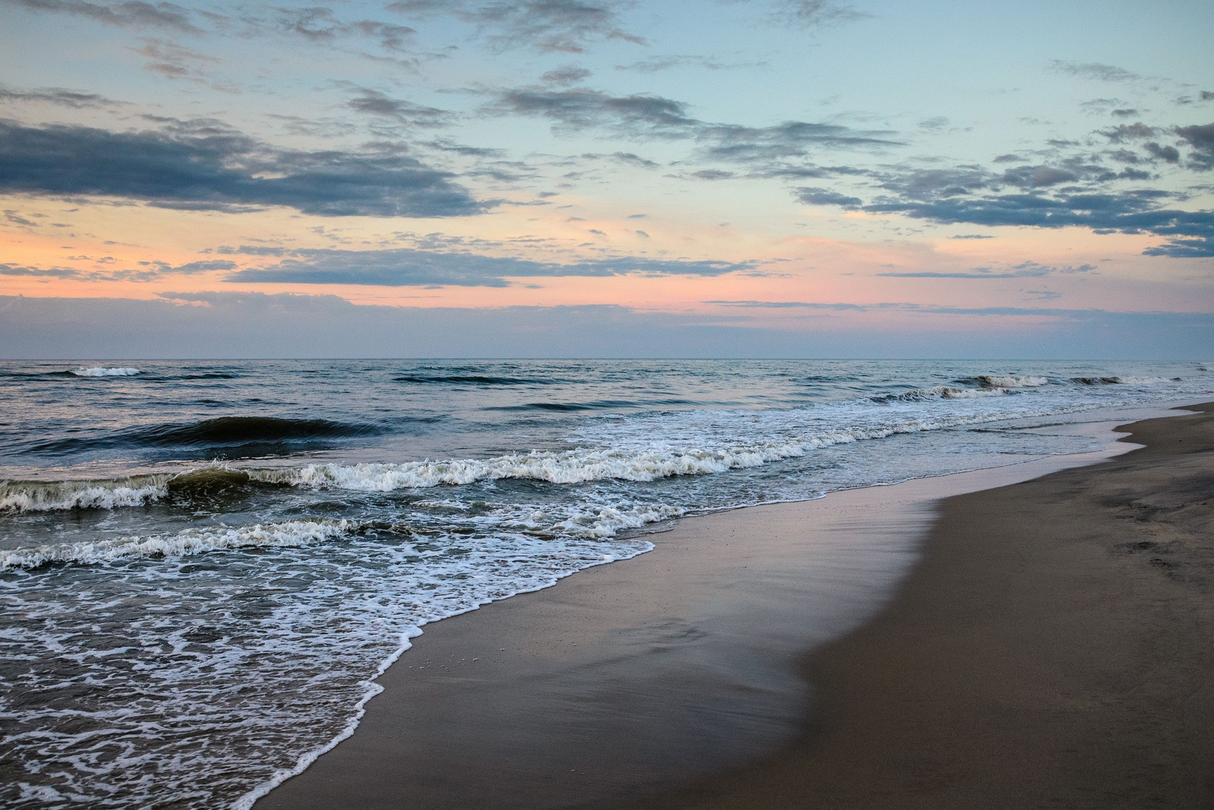 Beach during late sunset at Chincoteague Island, Virginia, ocean on the left, beach on the right, dark purples and oranges in the sky
