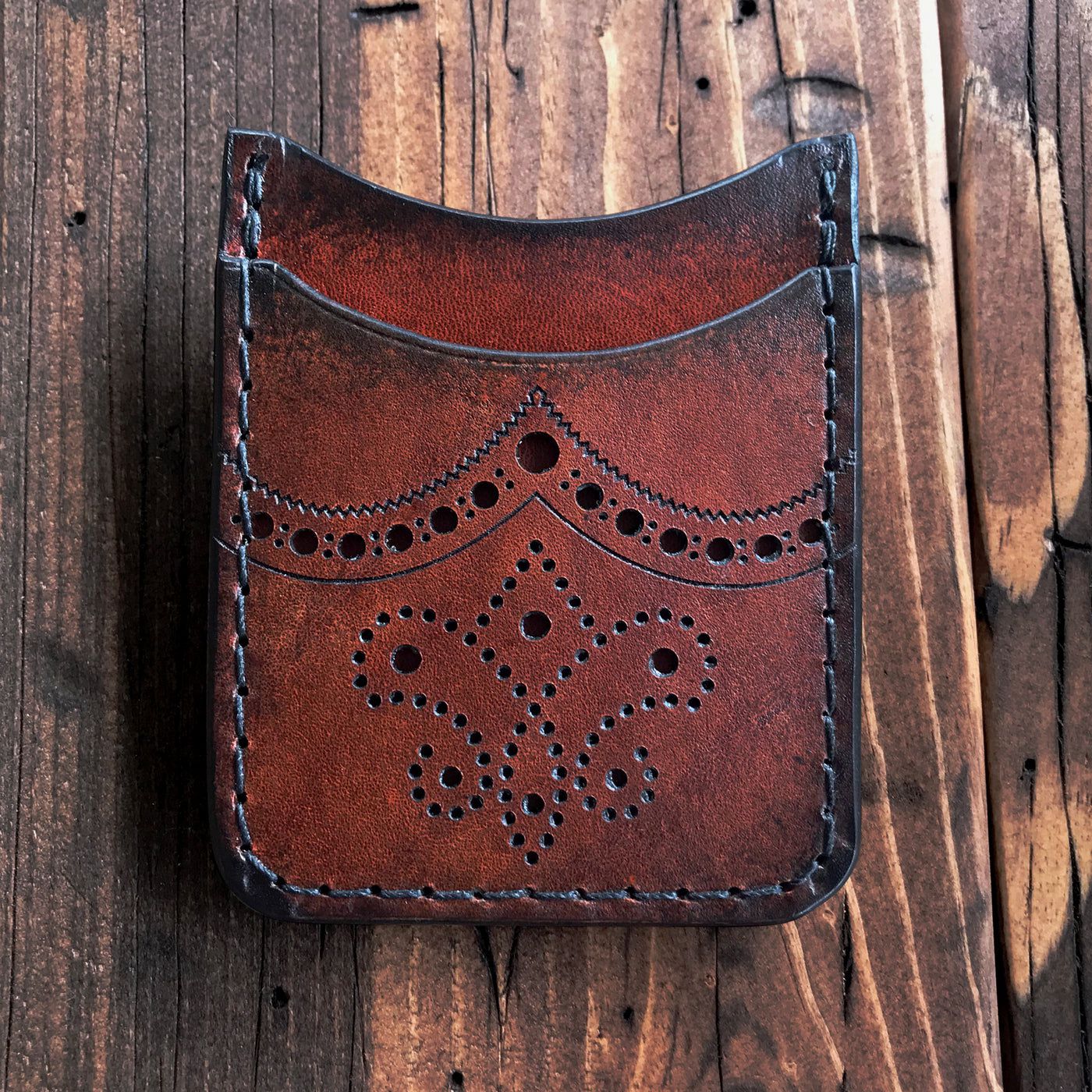 The Brogued Rover II Minimalist Wallet by Blackthorn Leather on rustic wood table