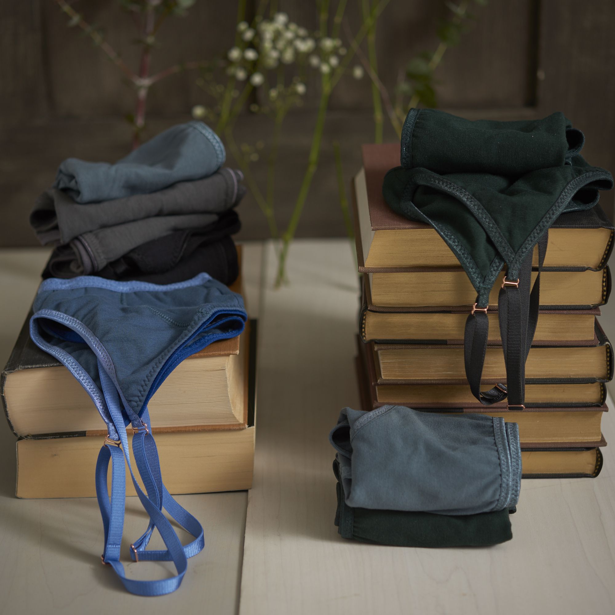 Blue and grey colored sports bras folded on stacks of books by Brook There