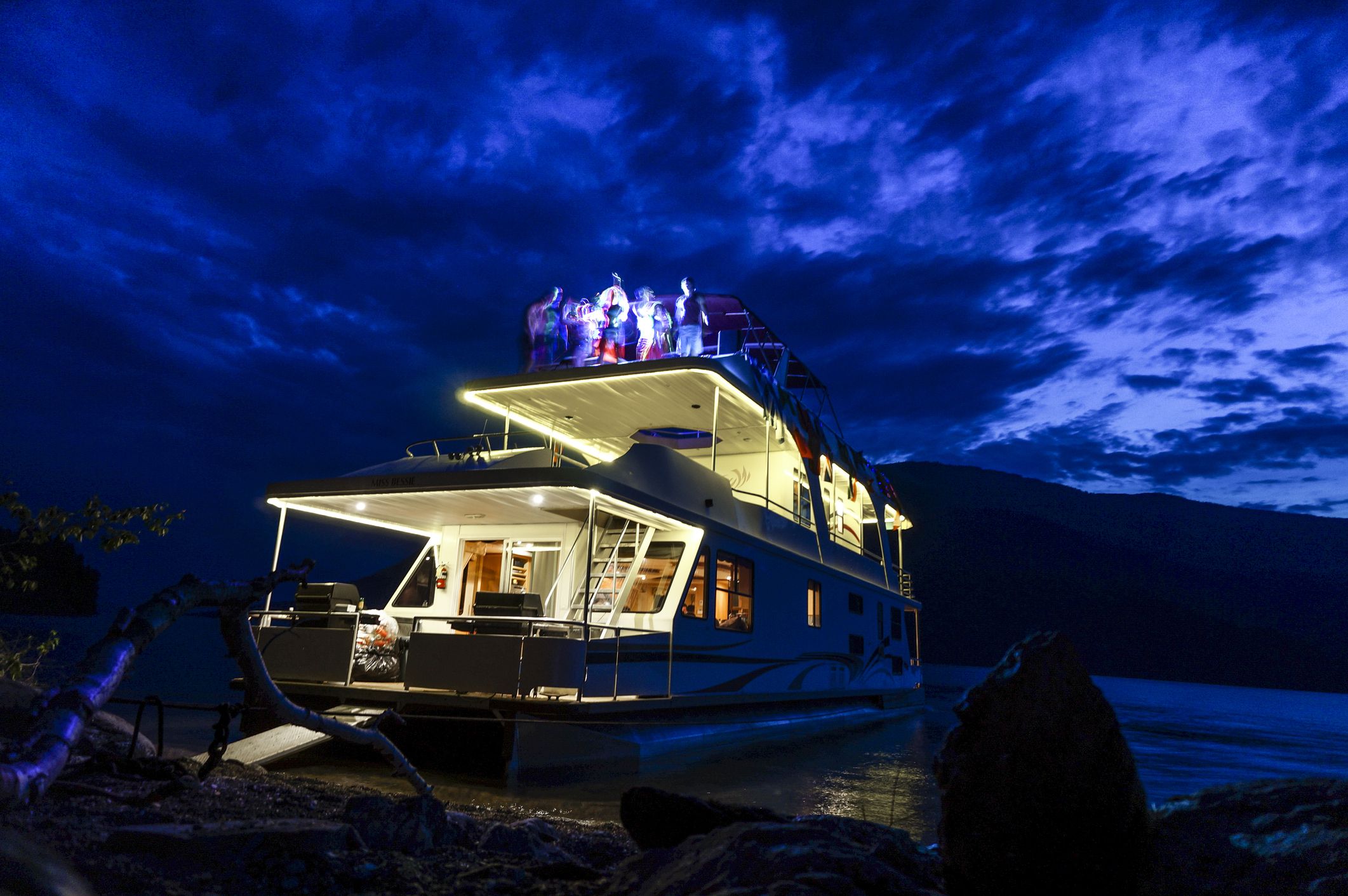 Dance party on a houseboat in Shuswap Lake, British Columbia, Canada, during twilight in the summer, dramatic indigo clouds in the background