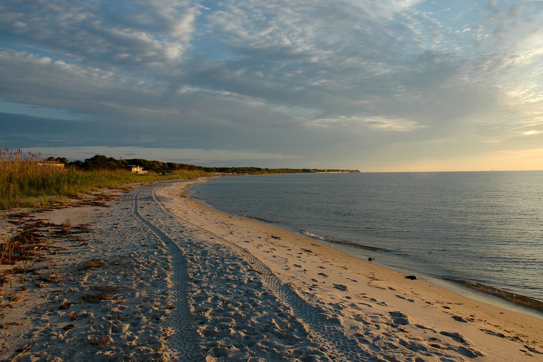 Empty beach during sunset on Fire Island, New York, beach in the foreground, grey and purple clouds in the sky