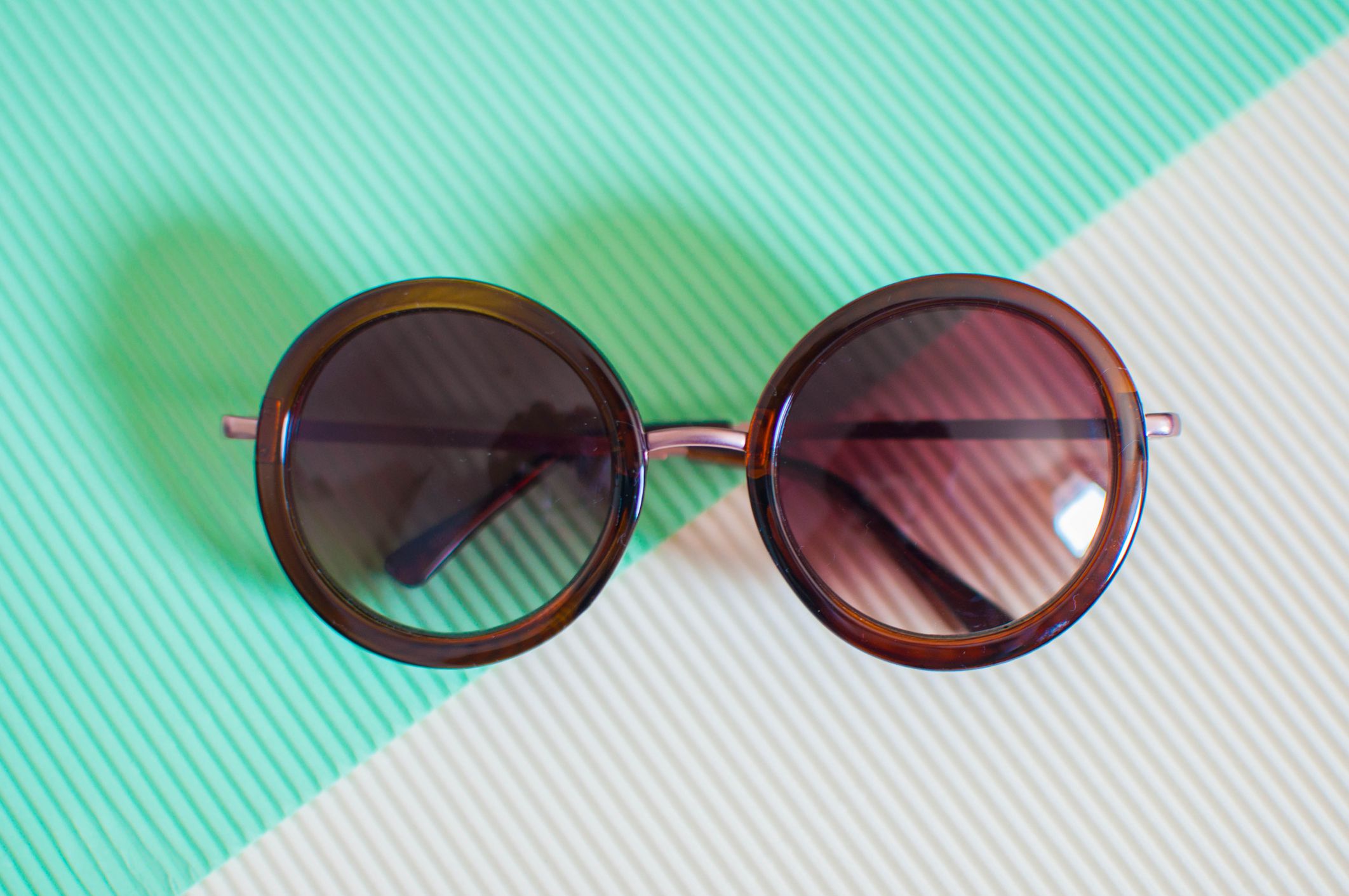 A flat lay of a pair of sunglasses against green and white background