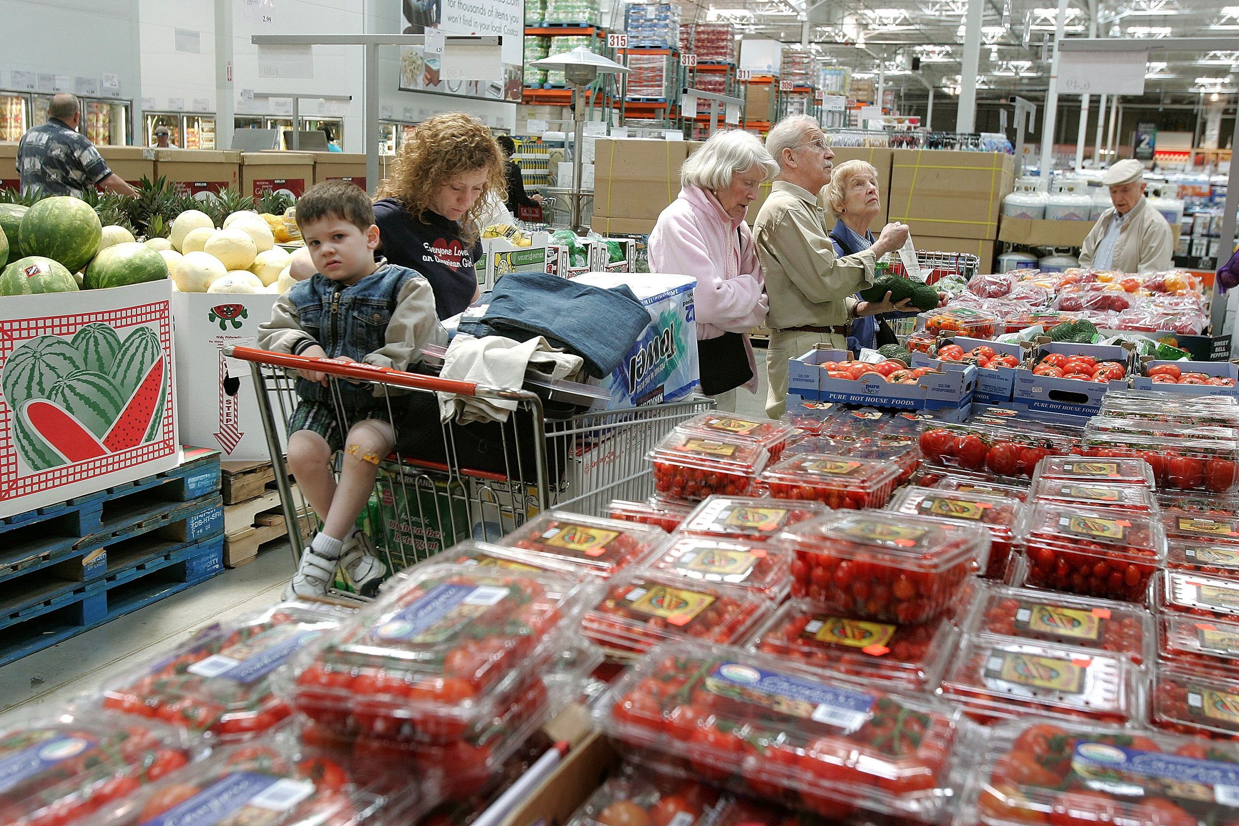 shoppers stand near the fruits and vegetables section at the Costco