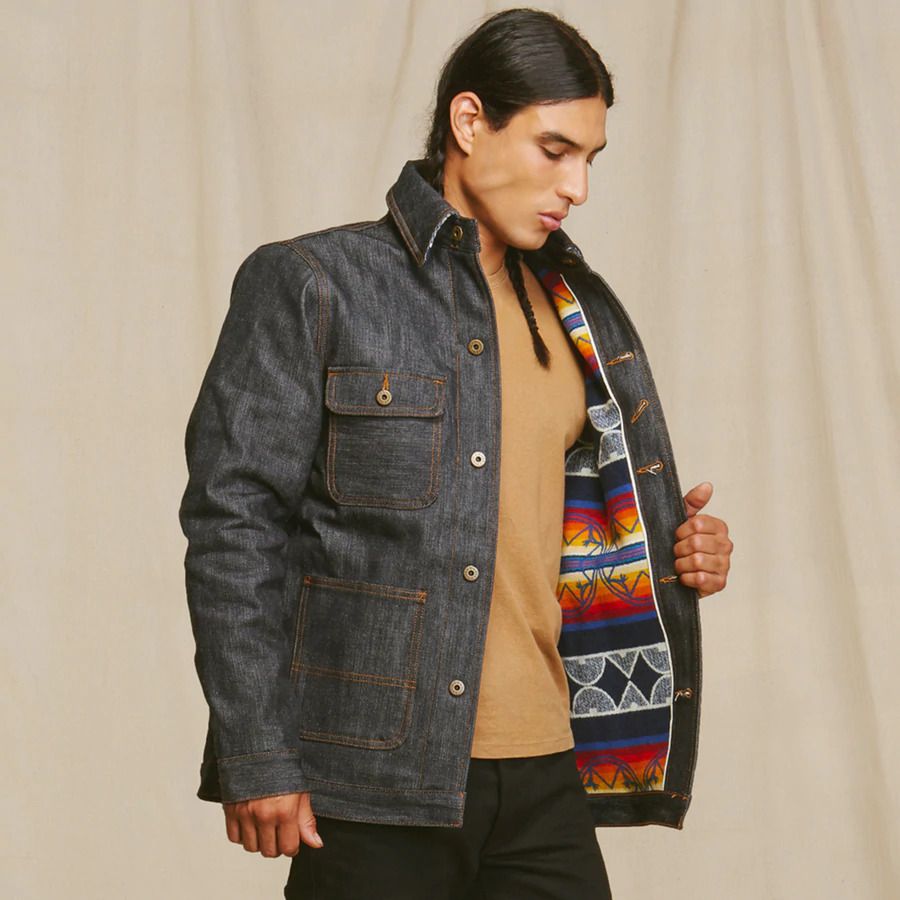 Model wearing Ginew jean jacket, beige knit jumper and black trousers