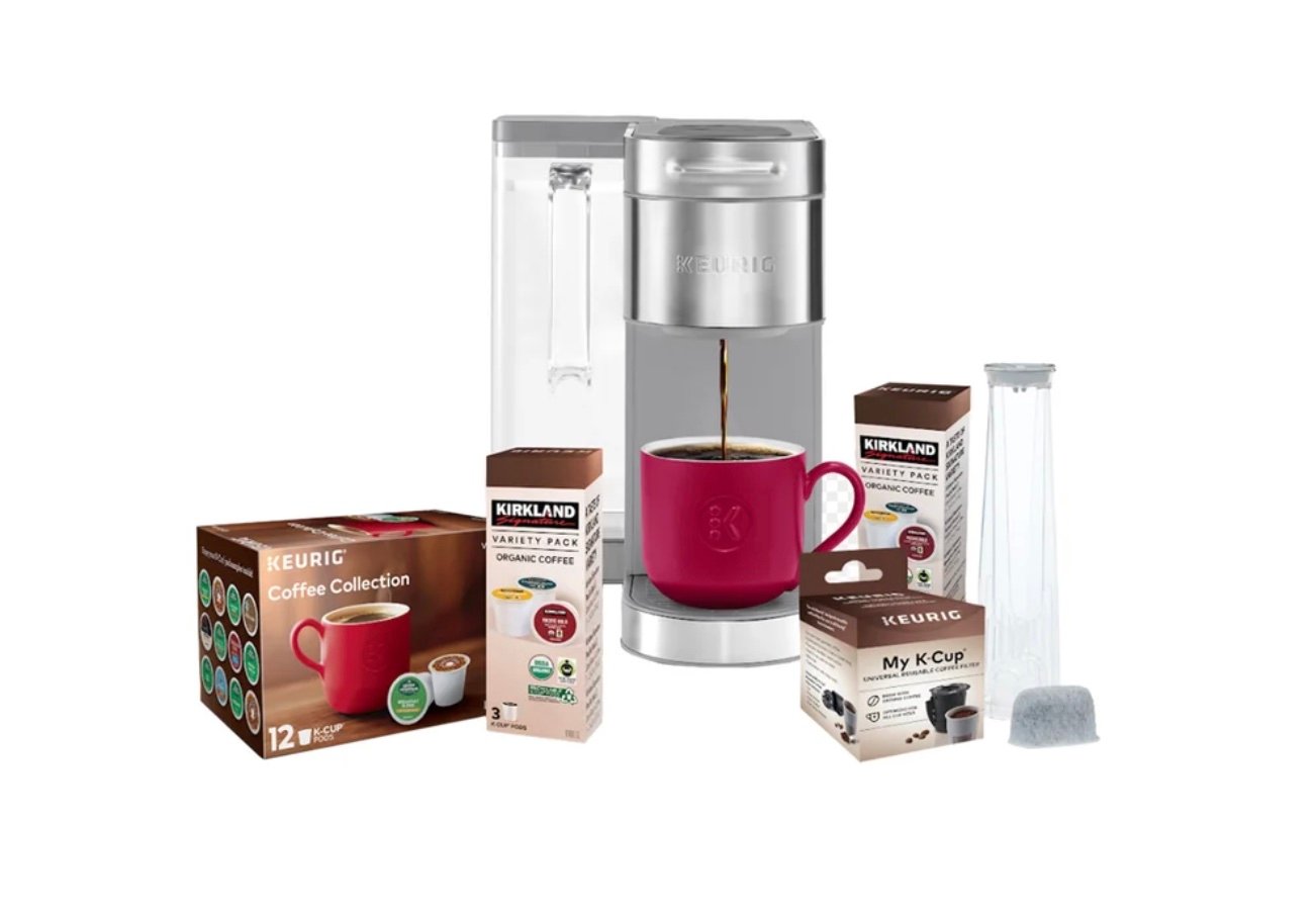 A silver Keurig coffee maker with a red mug beneath the dispenser, surrounded by boxes of K-Cup coffee pods, a My K-Cup reusable filter, and a water filter cartridge—one of the best Costco finds for coffee lovers.