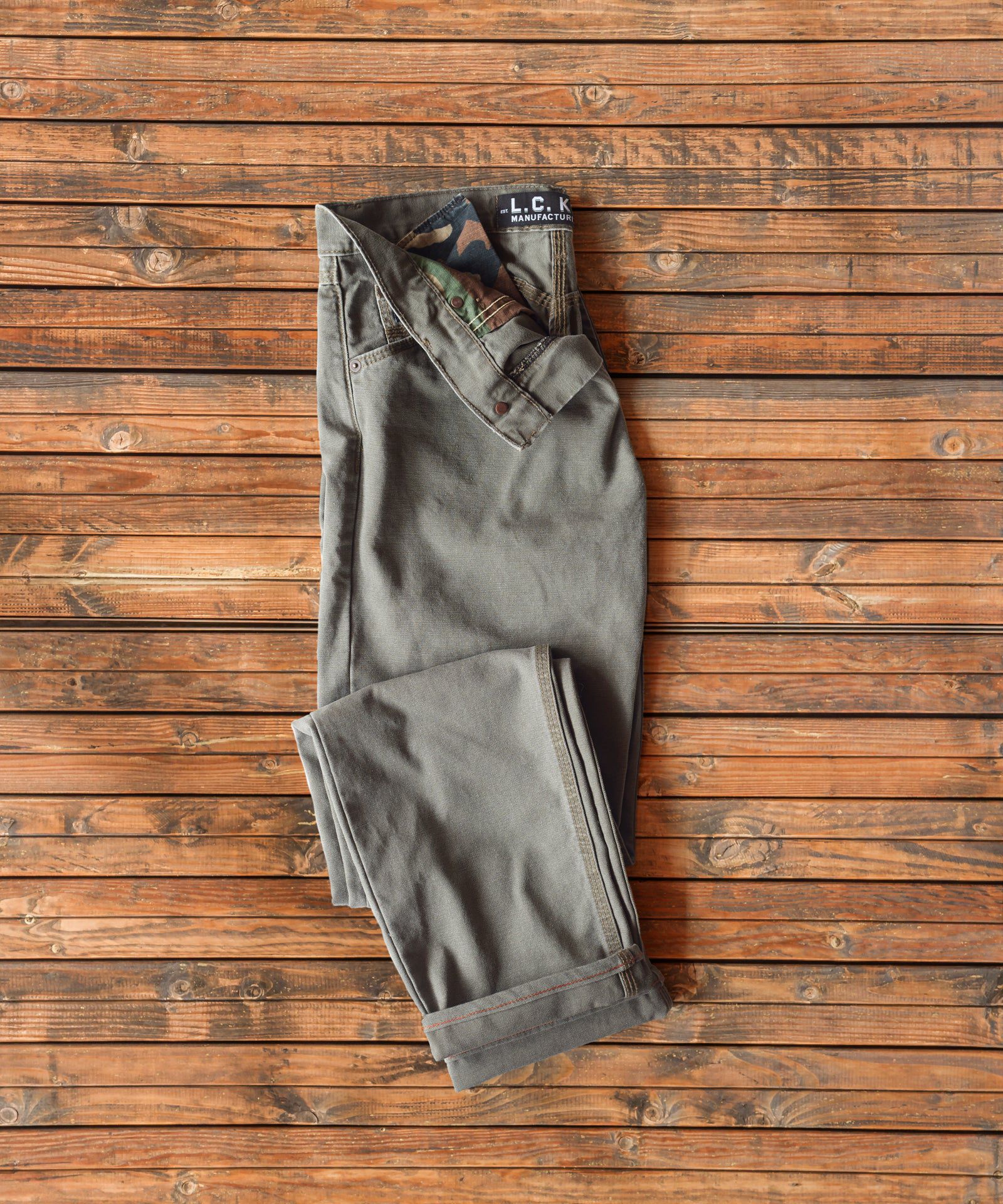 Green khaki colored LC King trousers on vintage wood floor boards