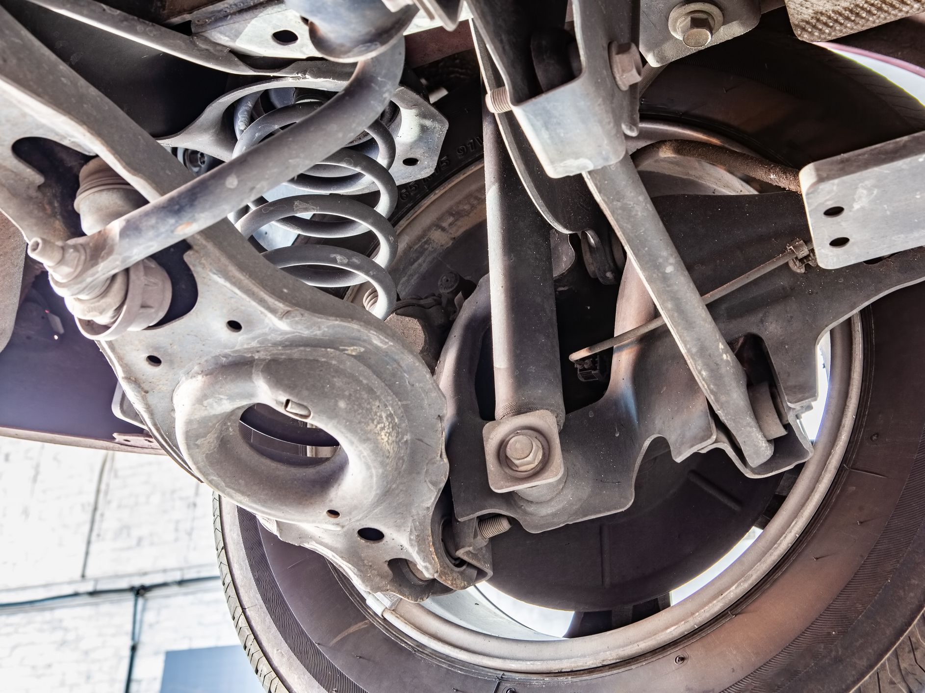 Inner part of car wheel with shock absorber, control arm and other mechanic parts during routine inspection in workshop