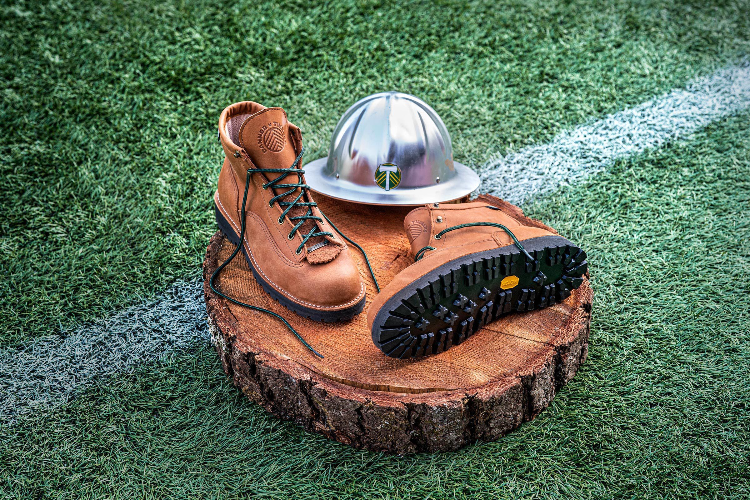 Pair of brown Danner boots with silver metal hat, all on wood sliver on a sports field