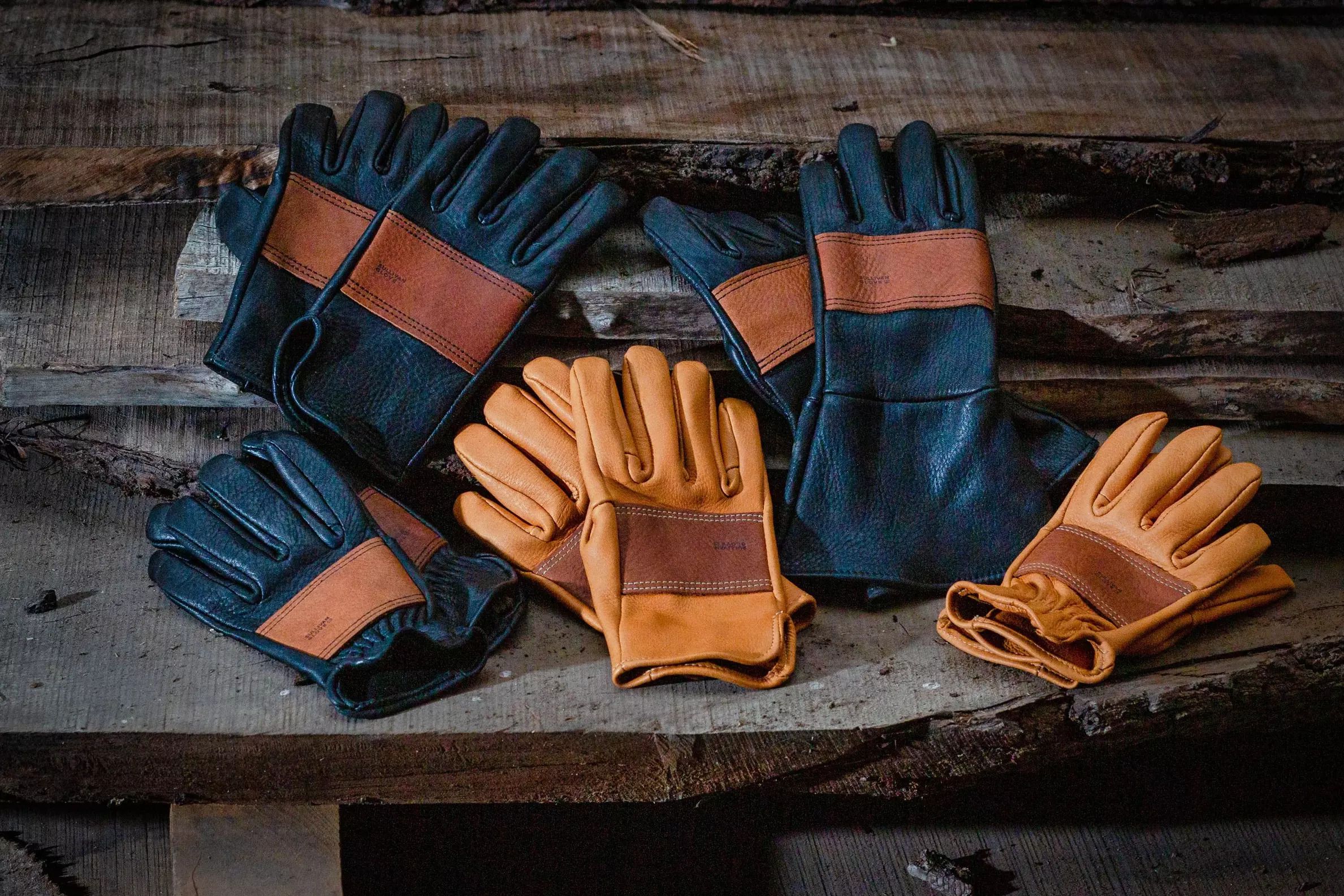 Three pairs of black and three pairs of tan leather gloves by Sullivan Glove Co. on very rustic table