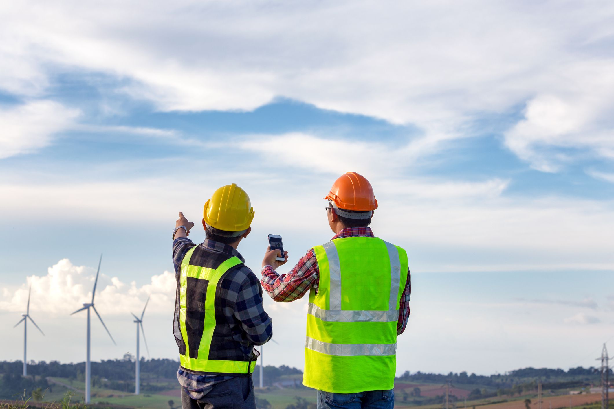 The engineers standing outdoor survey wind turbines green energy together and analysis energy of wind turbine construction this is electric energy.