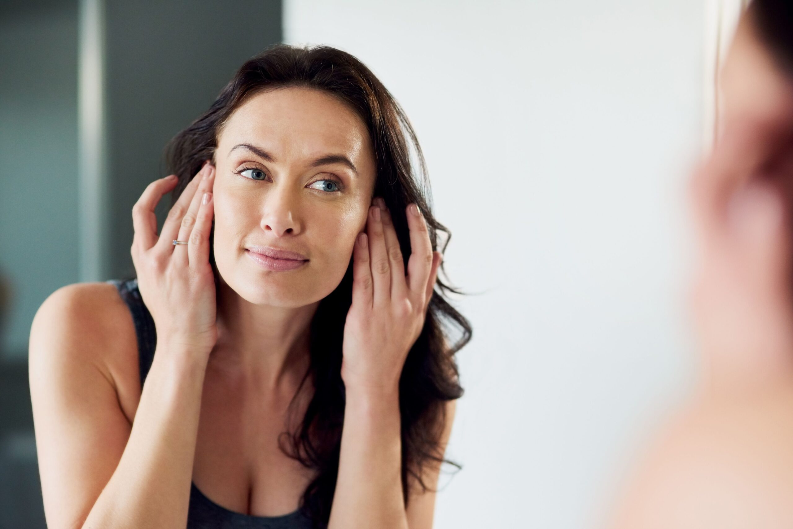 woman looking at face in mirror