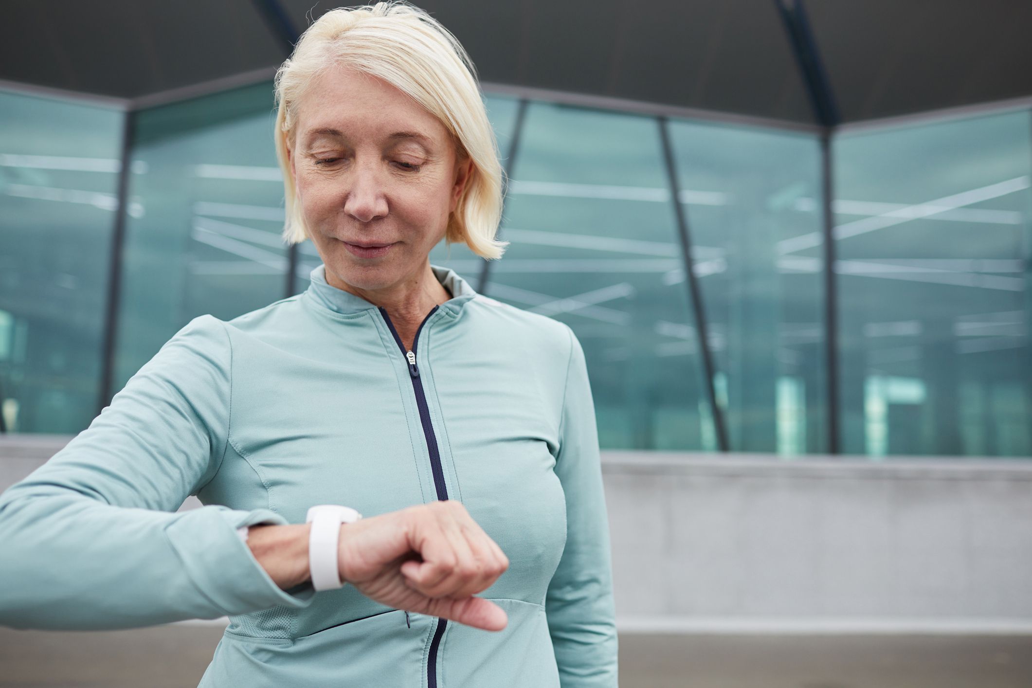 sportswoman looking at her wristwatch while getting ready for jog training in urban environment