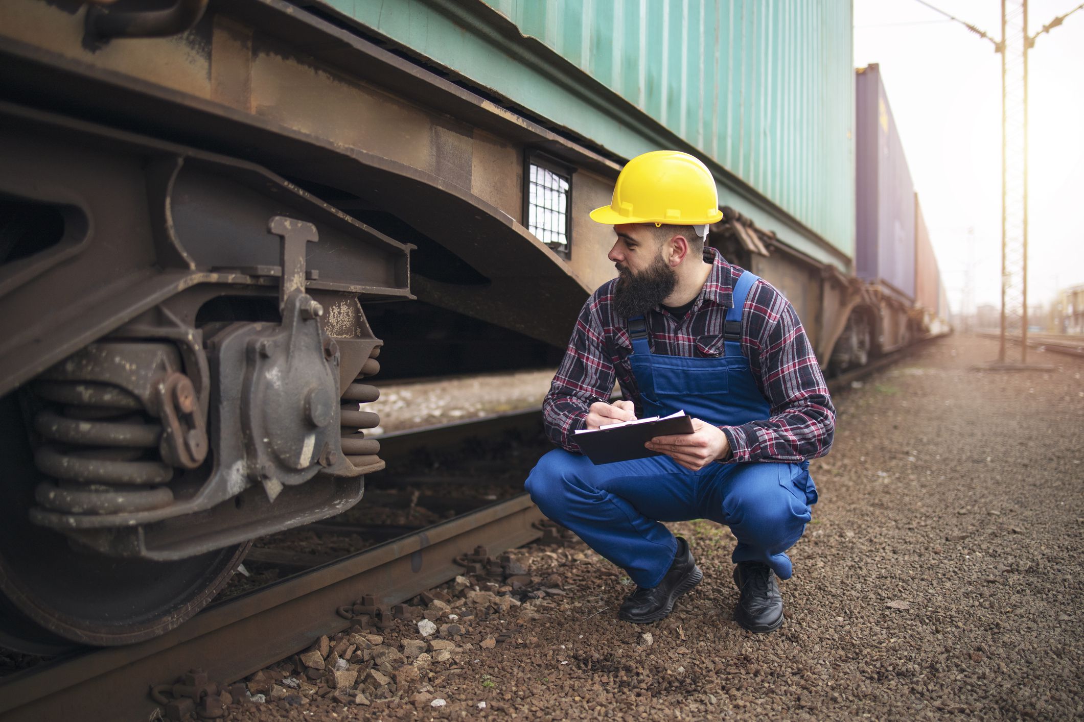 Caucasian train engineer with clipboard inspecting train at the station.