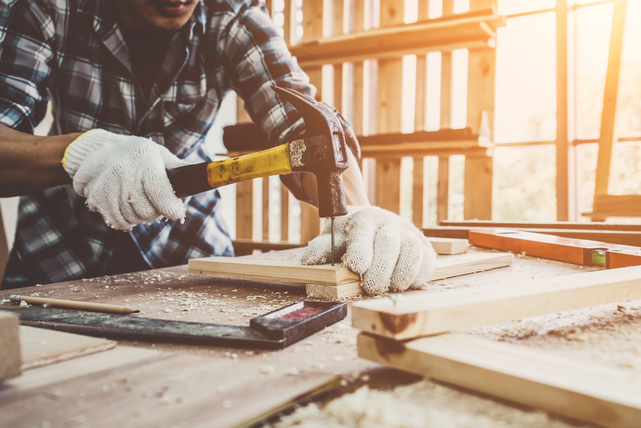 Carpenter working on wood craft at workshop to produce construction material or wooden furniture. The young Asian carpenter use professional tools for crafting. DIY maker and carpentry work concept.