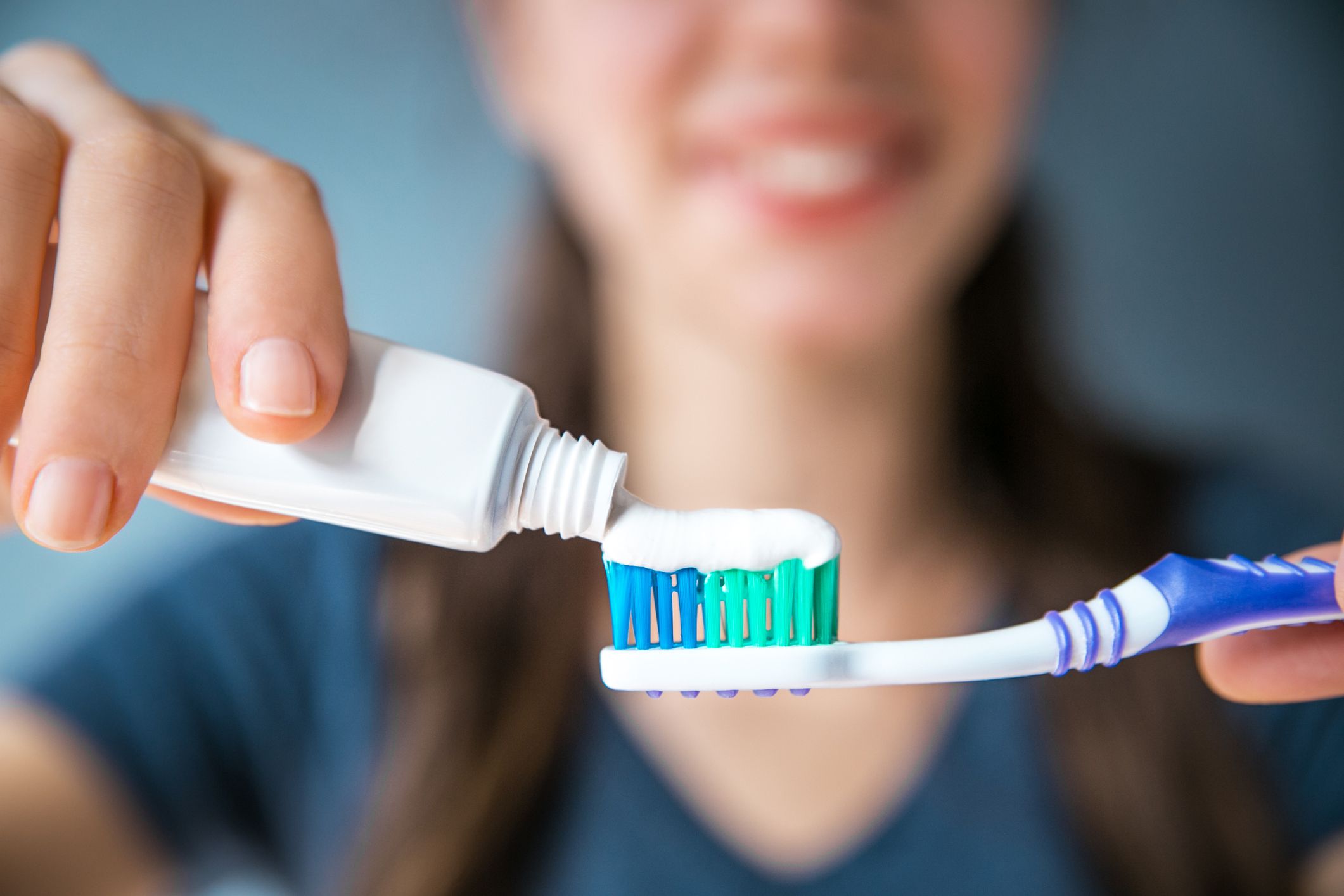 close-up of young woman putting toothpaste on toothbrush