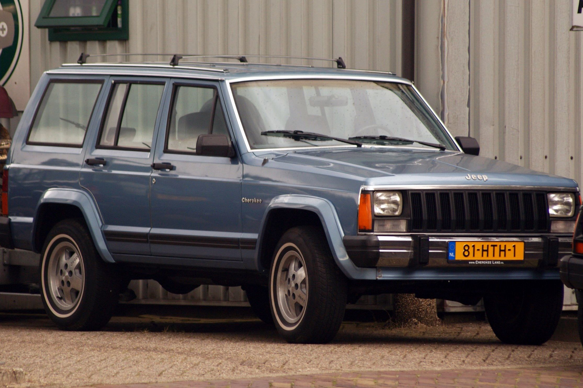 Blue 1985 Jeep Cherokee XJ parked on street.