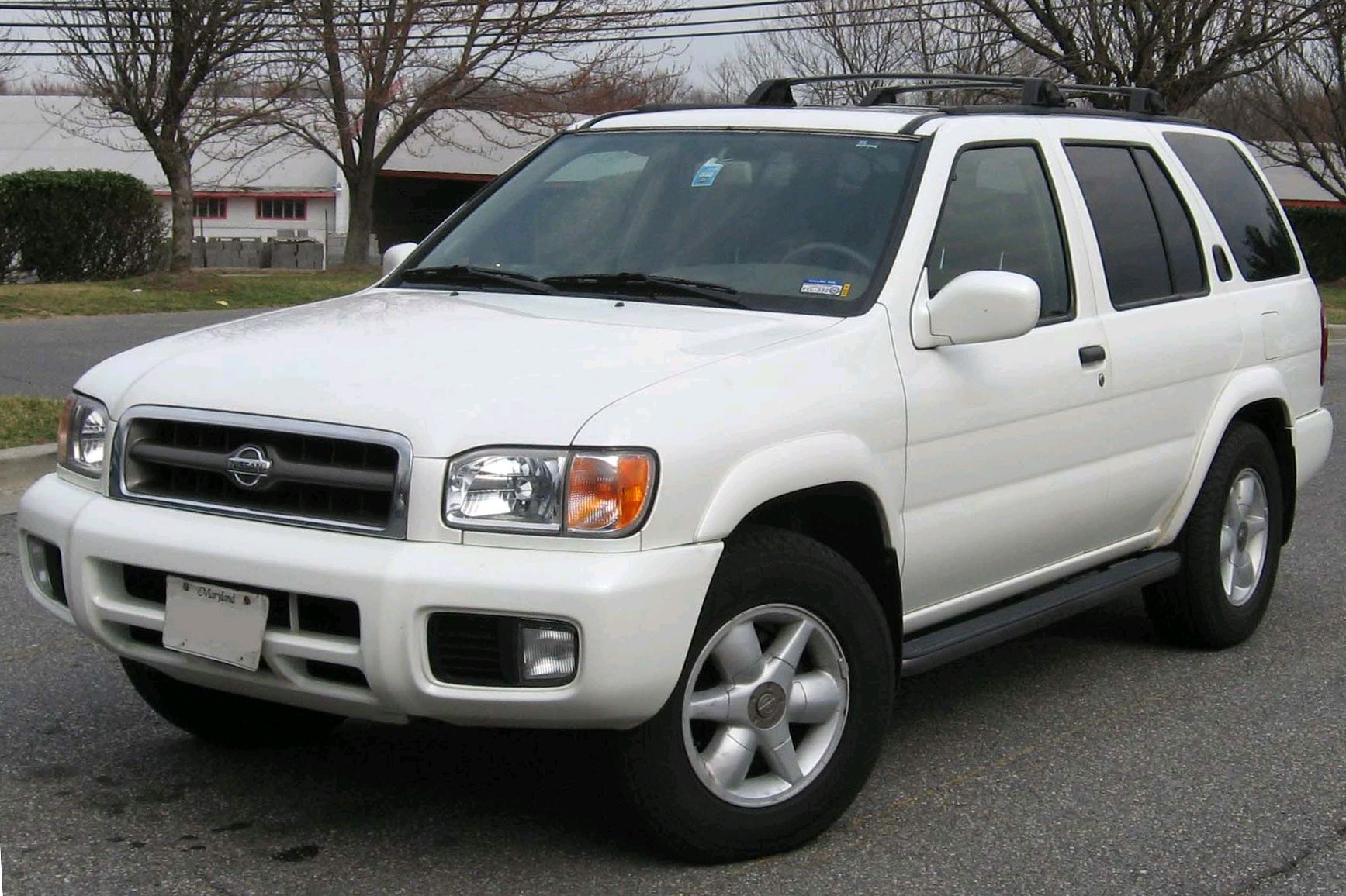 White 2002 Nissan Pathfinder parked on street on gray day.