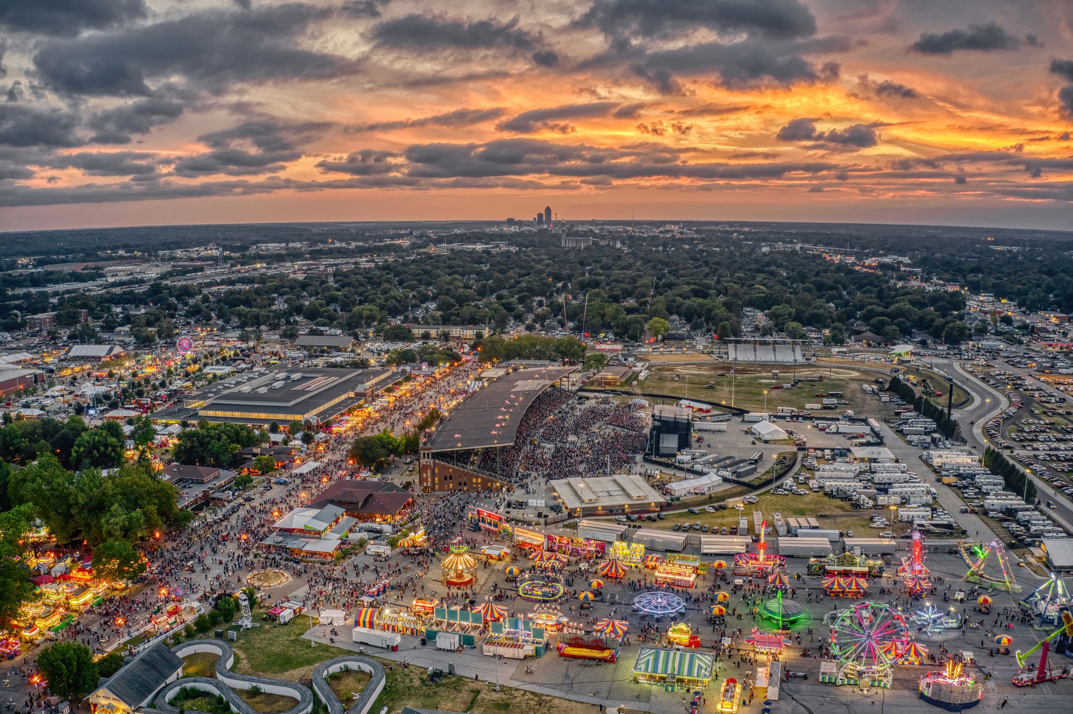Aerial of the Iowa State Fair in Des Moines, Iowa, lights on rides during early evening, sun set colors in the sky