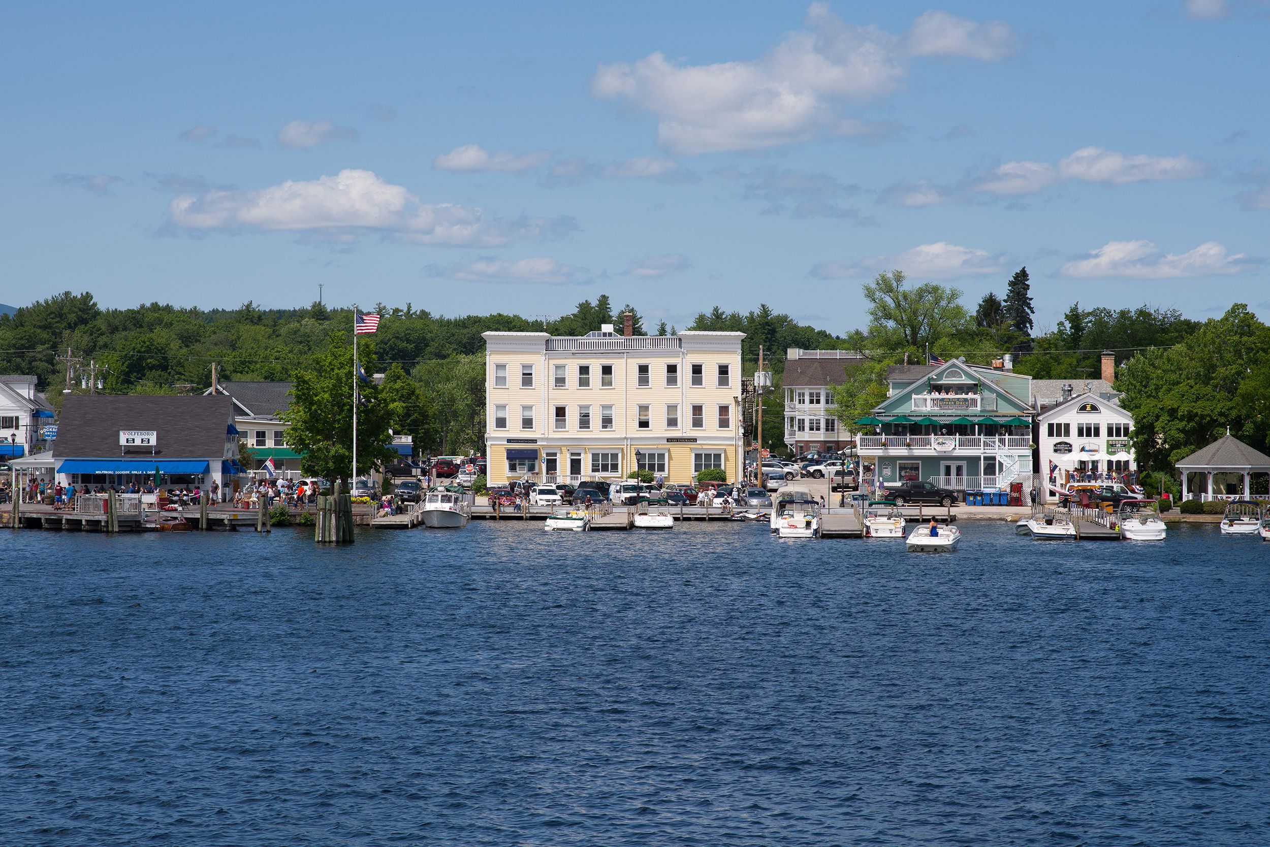 Boats in slips along the side of Wolfeboro, New Hampshire, buildings of town, river in the foreground