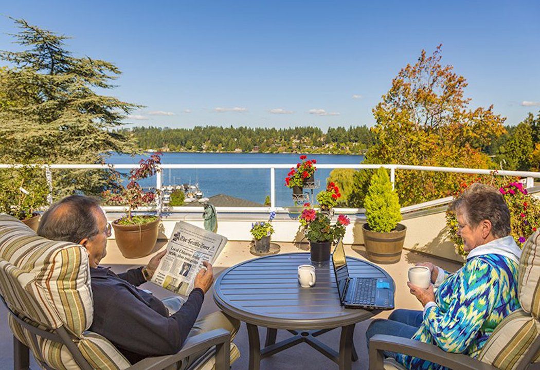 Couple reading the paper on a deck overlooking a lake in Covenant living at the shores