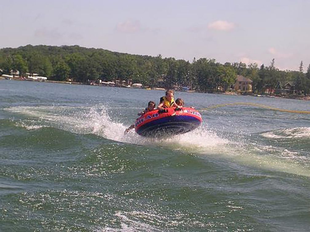 Three kids water tubing on a lake in Minnesota.
