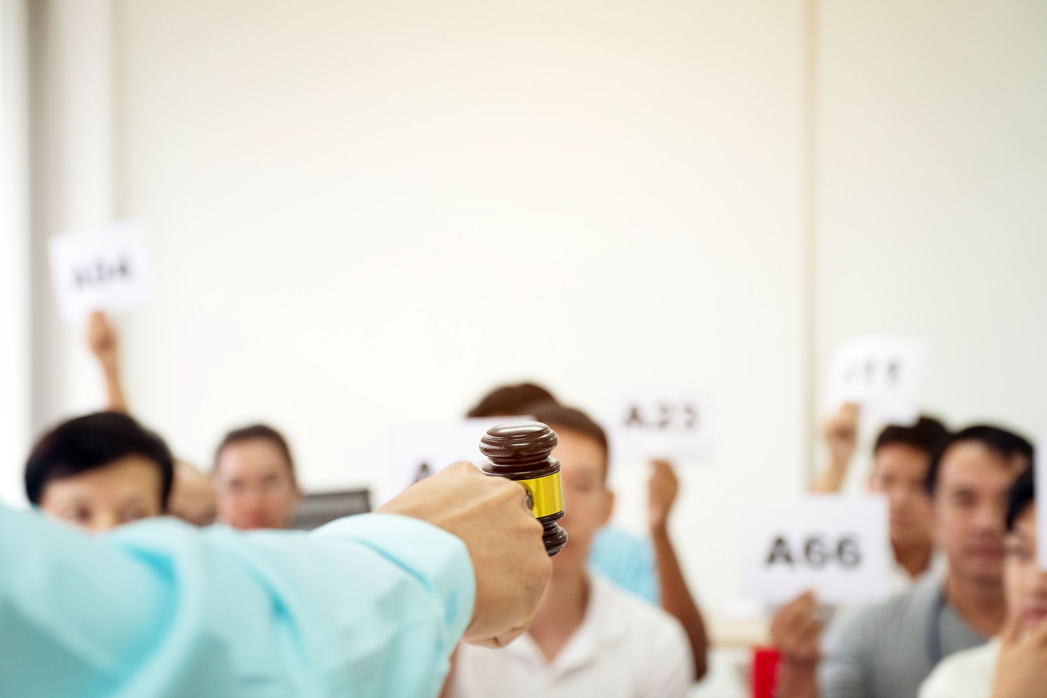 bidders in auction in background, close-up of gavel in foreground
