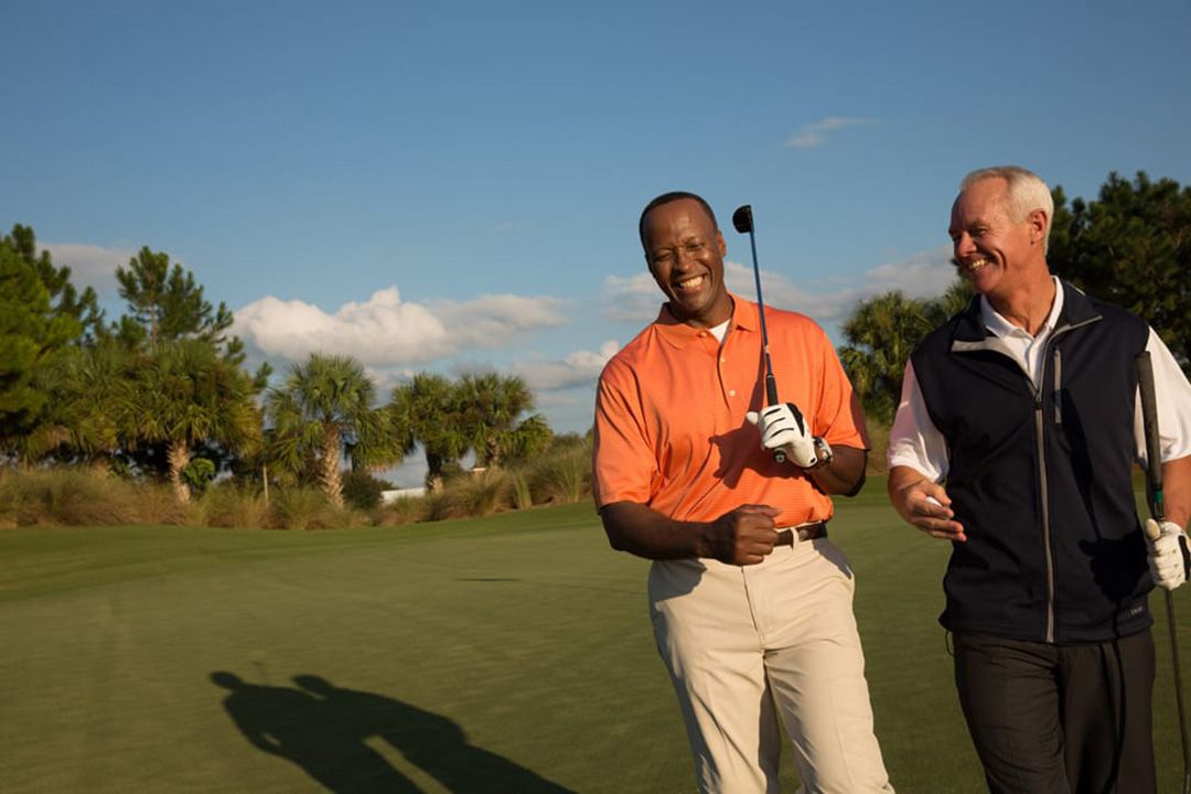 Two men walking on golf course while laughing