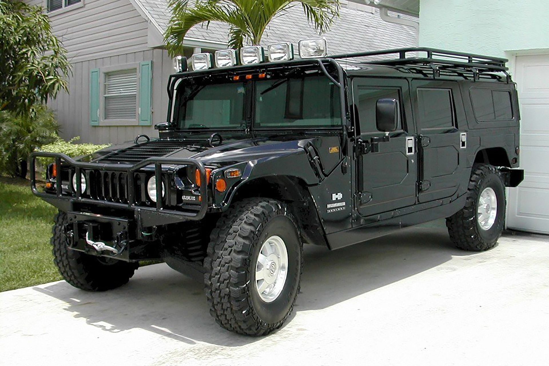 Hummer H1 parked in front of house next to palm tree